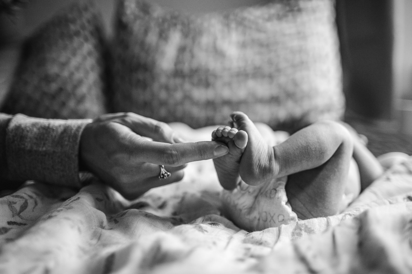 black and white image of mother touching newborn baby feet during pictures
