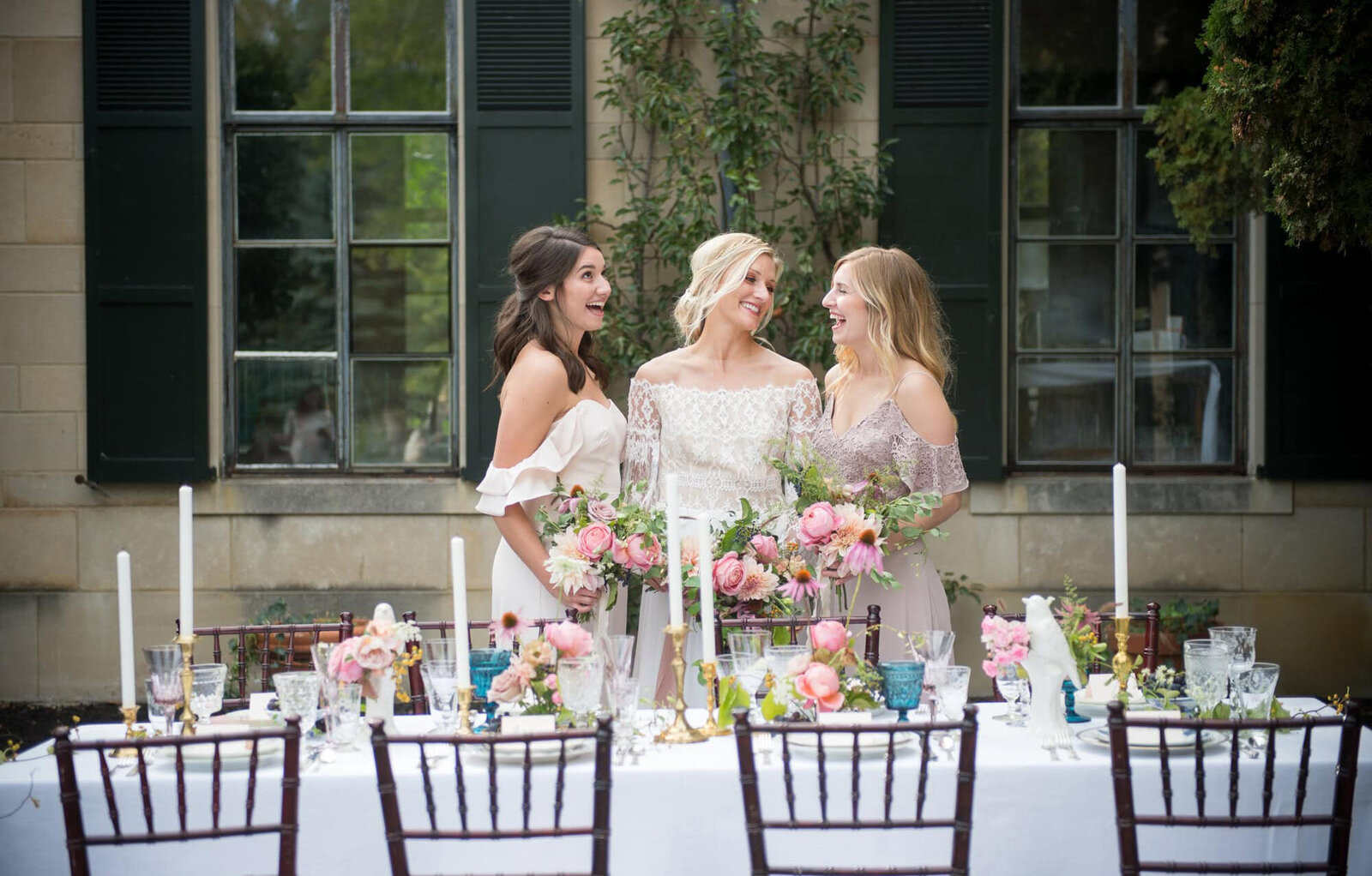 bride and bridesmaids smile together in front of floral table