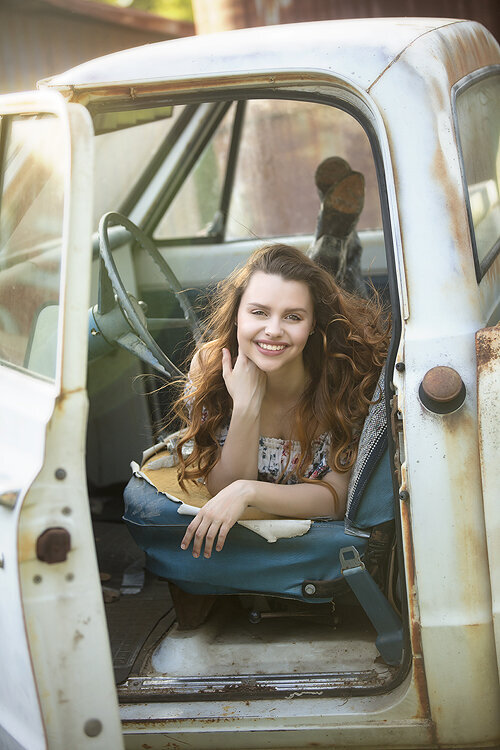 Senior girl poses in truck at a farm