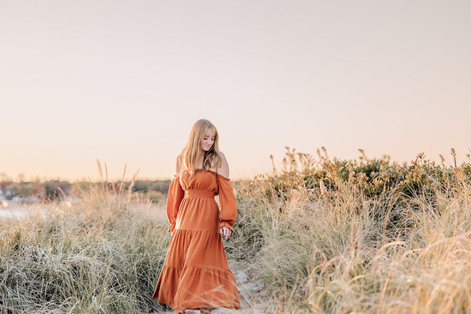 high school senior girl in orange dress in tall grass