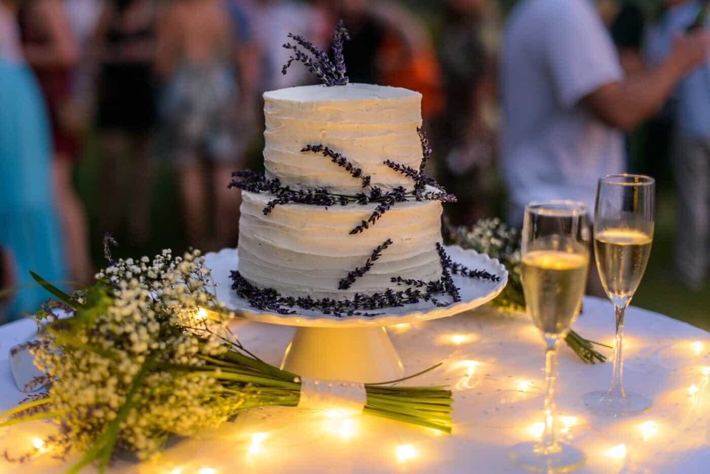 A simple white buttercream cake decorated with lavender on a table during a wedding in Northern Virginia