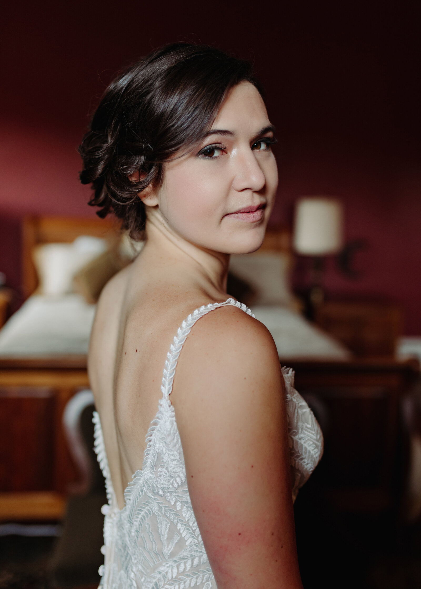 A bride in a vintage wedding dress looks at the camera