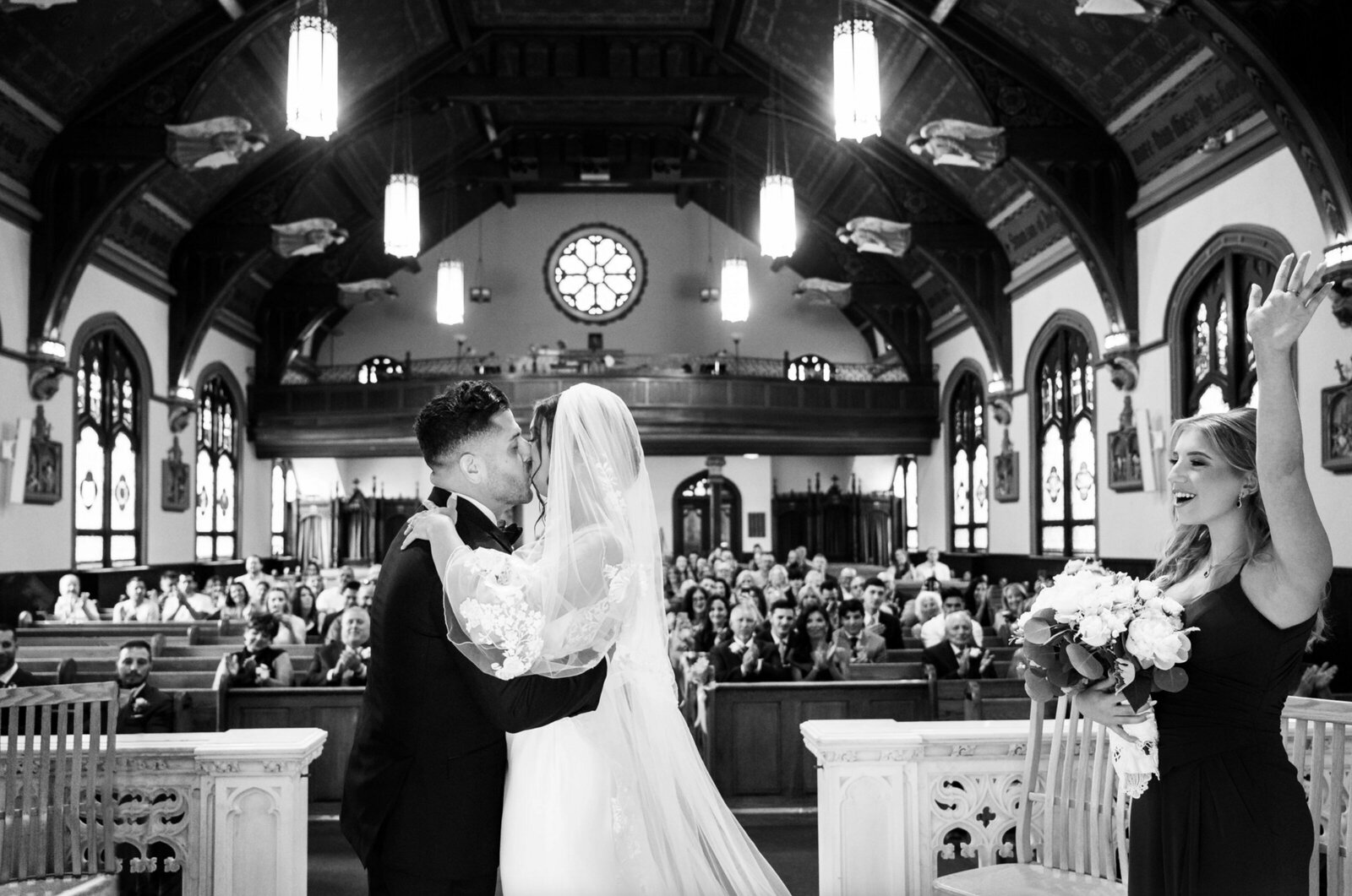 bride and groom, kissing after being pronounced, man and wife, inside of Saint peters Church in point Pleasant Beach with the audience in the background