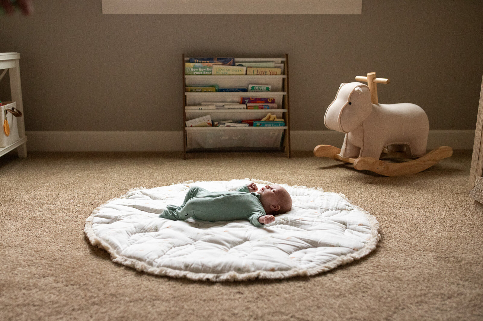 Infant laying on round rug in the middle of his nursery.