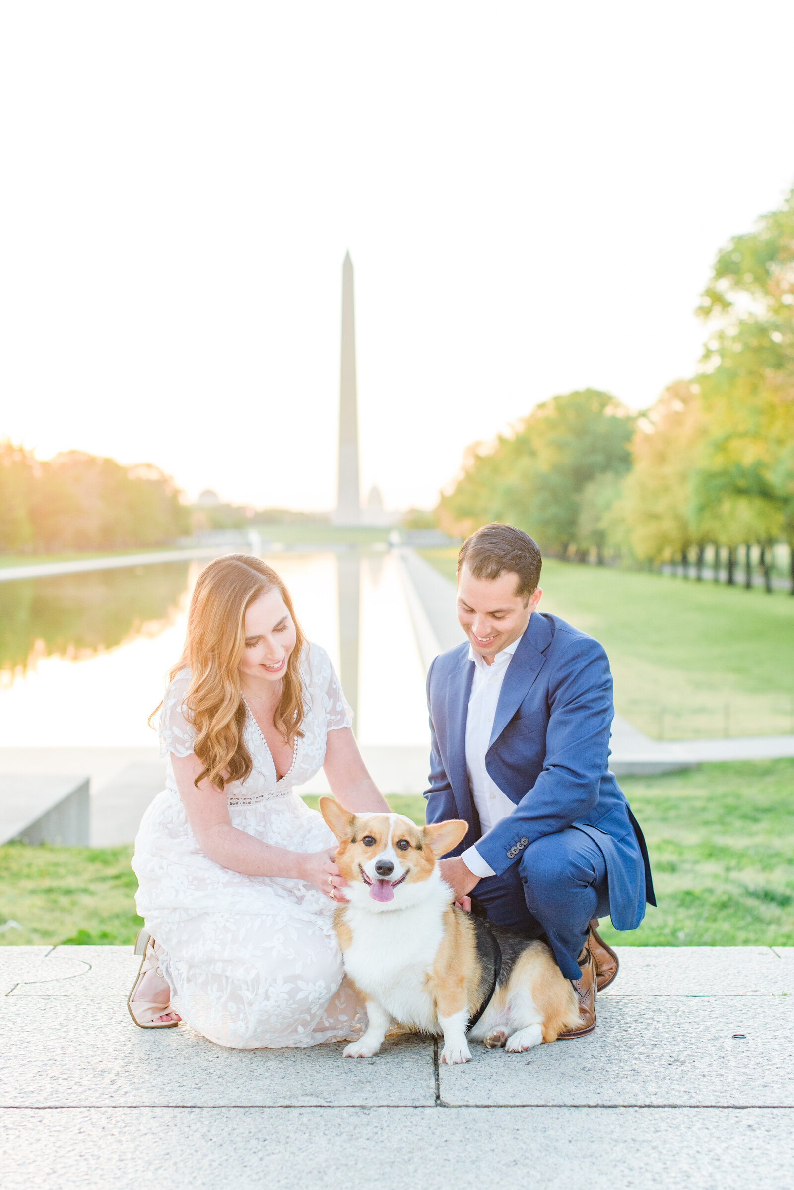 Couple smiles with their corgi during sunrise engagement session at the Lincoln Memorial
