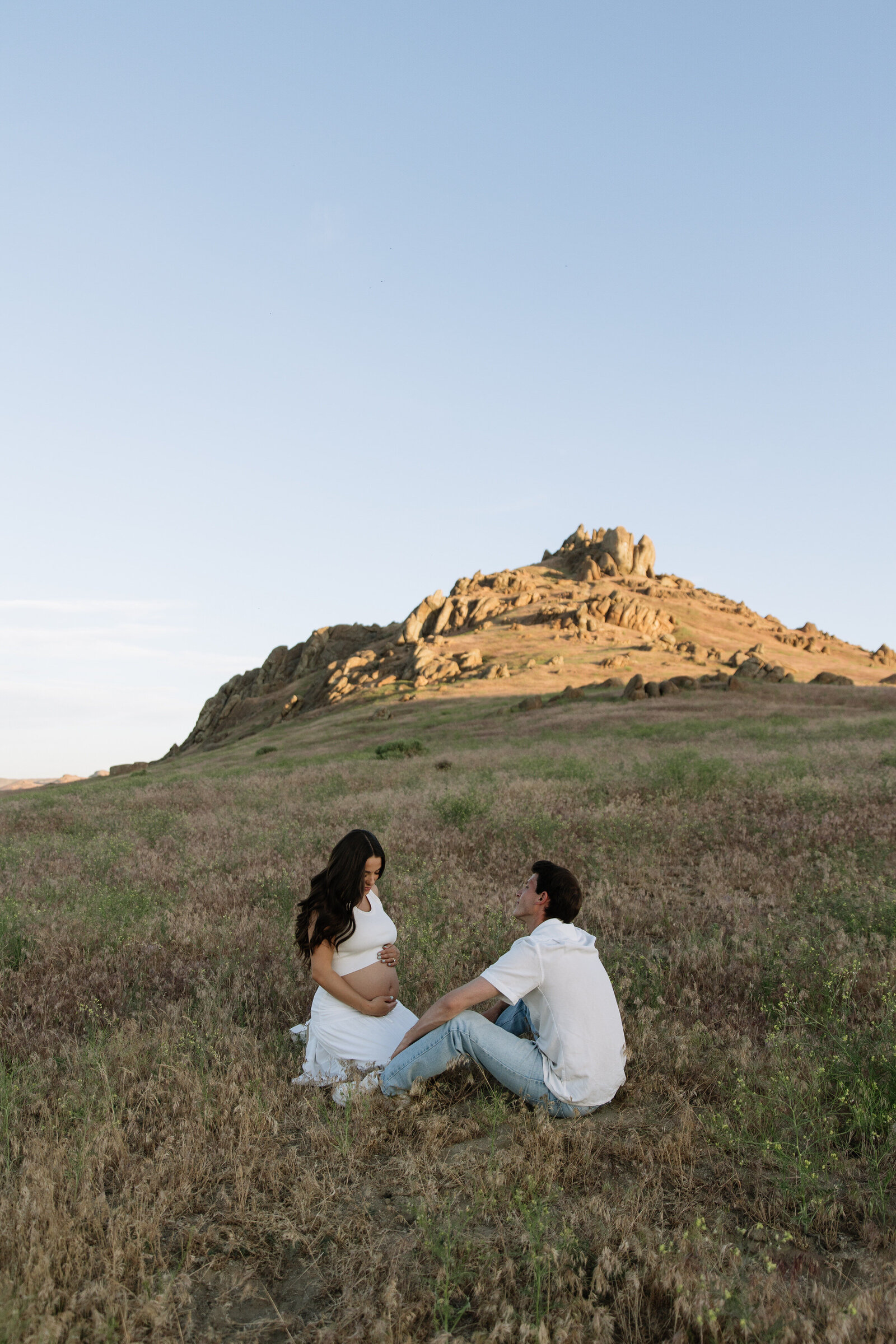 Romantic sitting pose of couple during maternity session with nature views