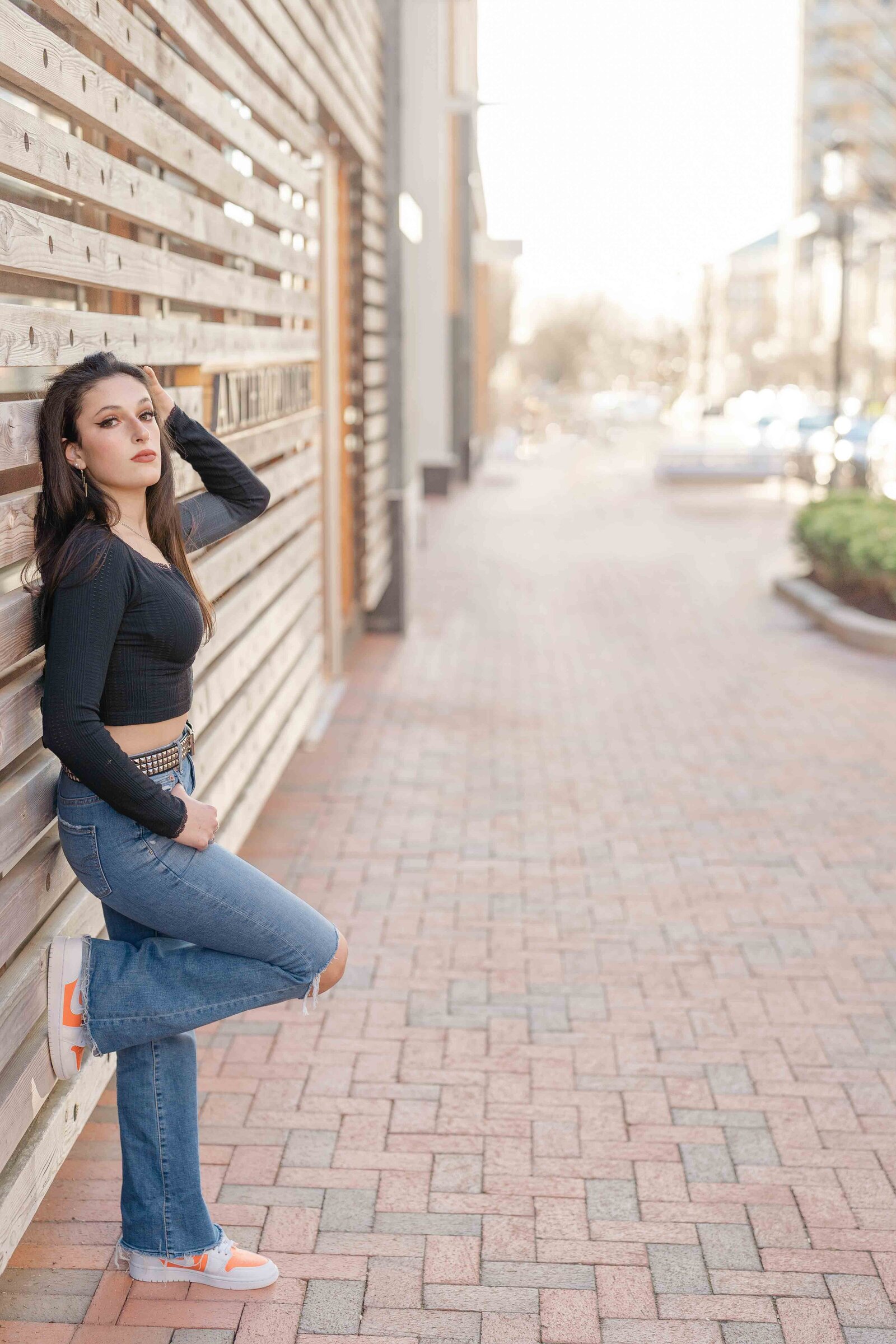 girl leaning on a wall with foot up during senior photo in Reston, VA