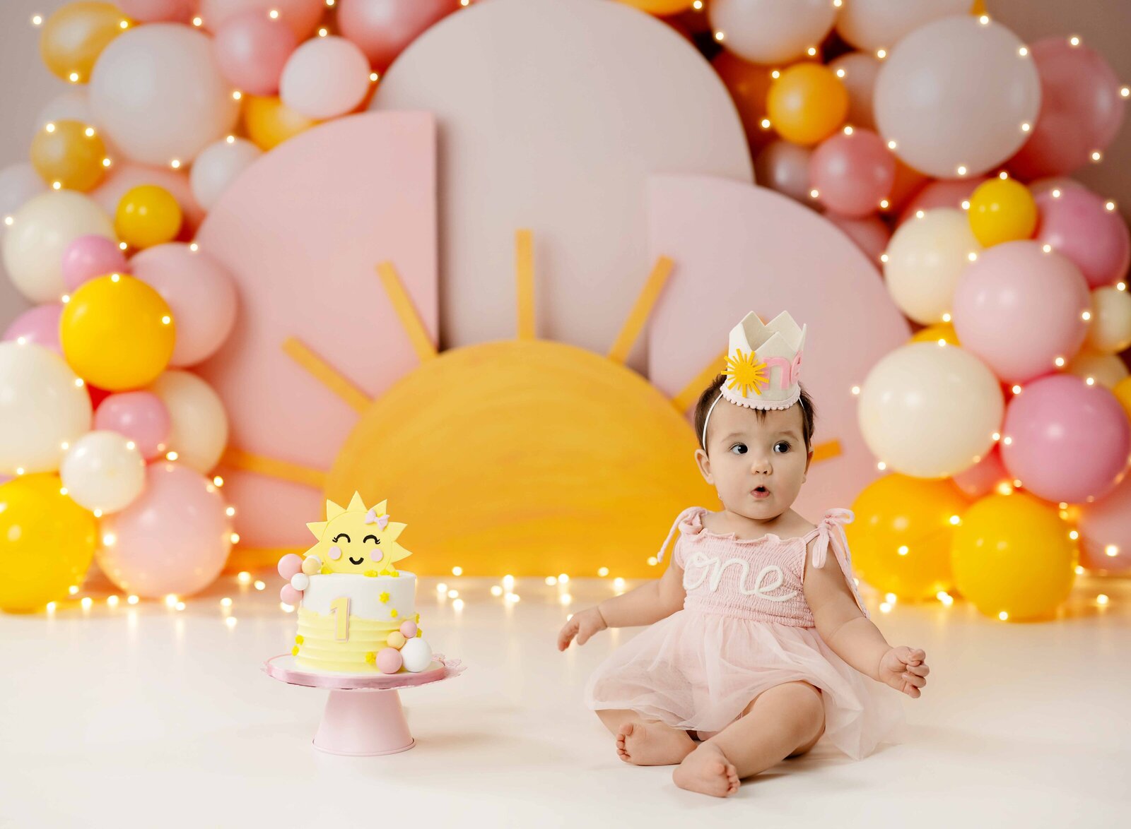 Baby girl sitting next to cake with a big surprise on her face.