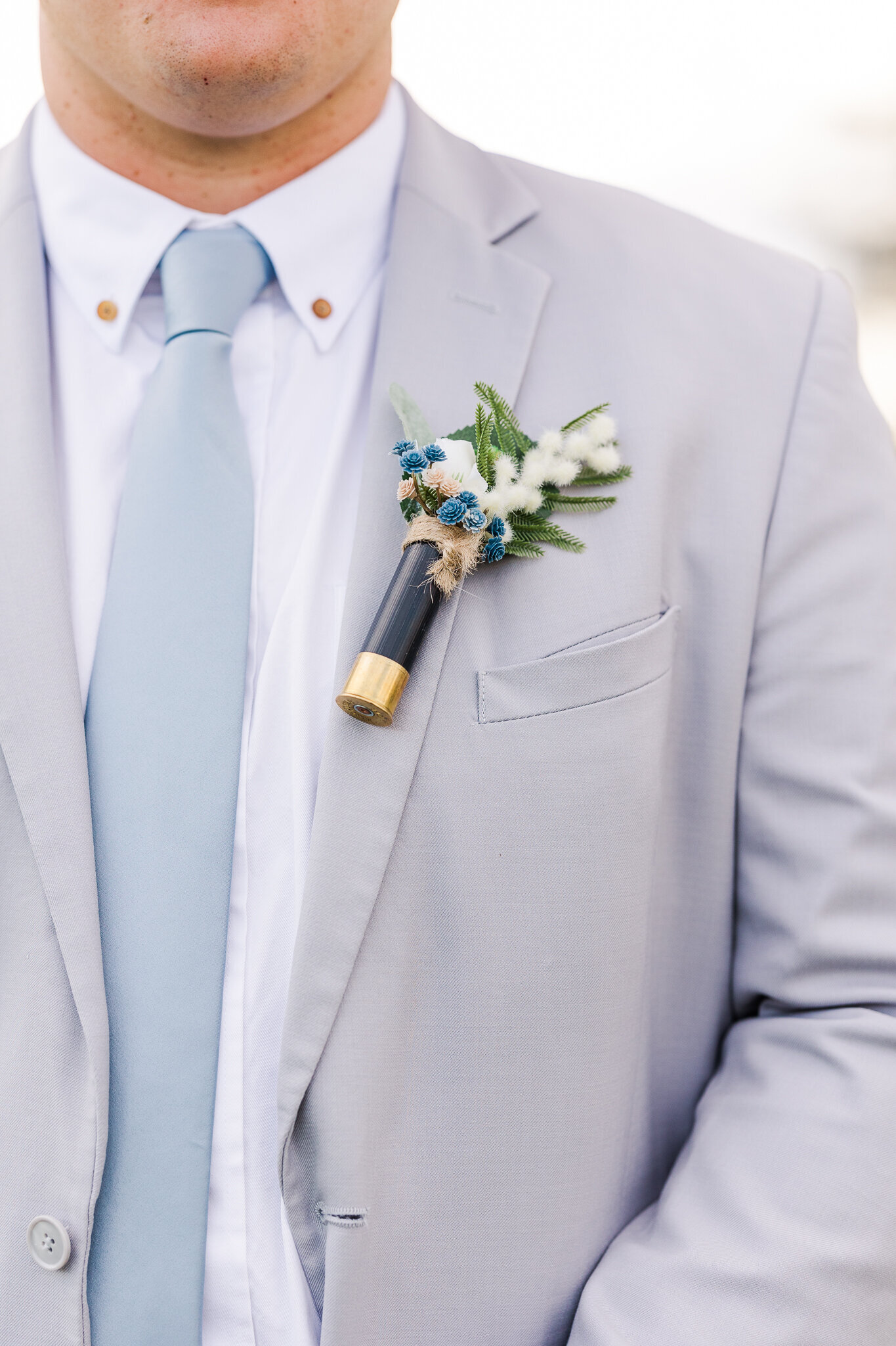 Close-up of boutonniere on the groom’s gray suit jacket at a Loma, Colorado wedding at Absolute Prestige Limo and Venue.