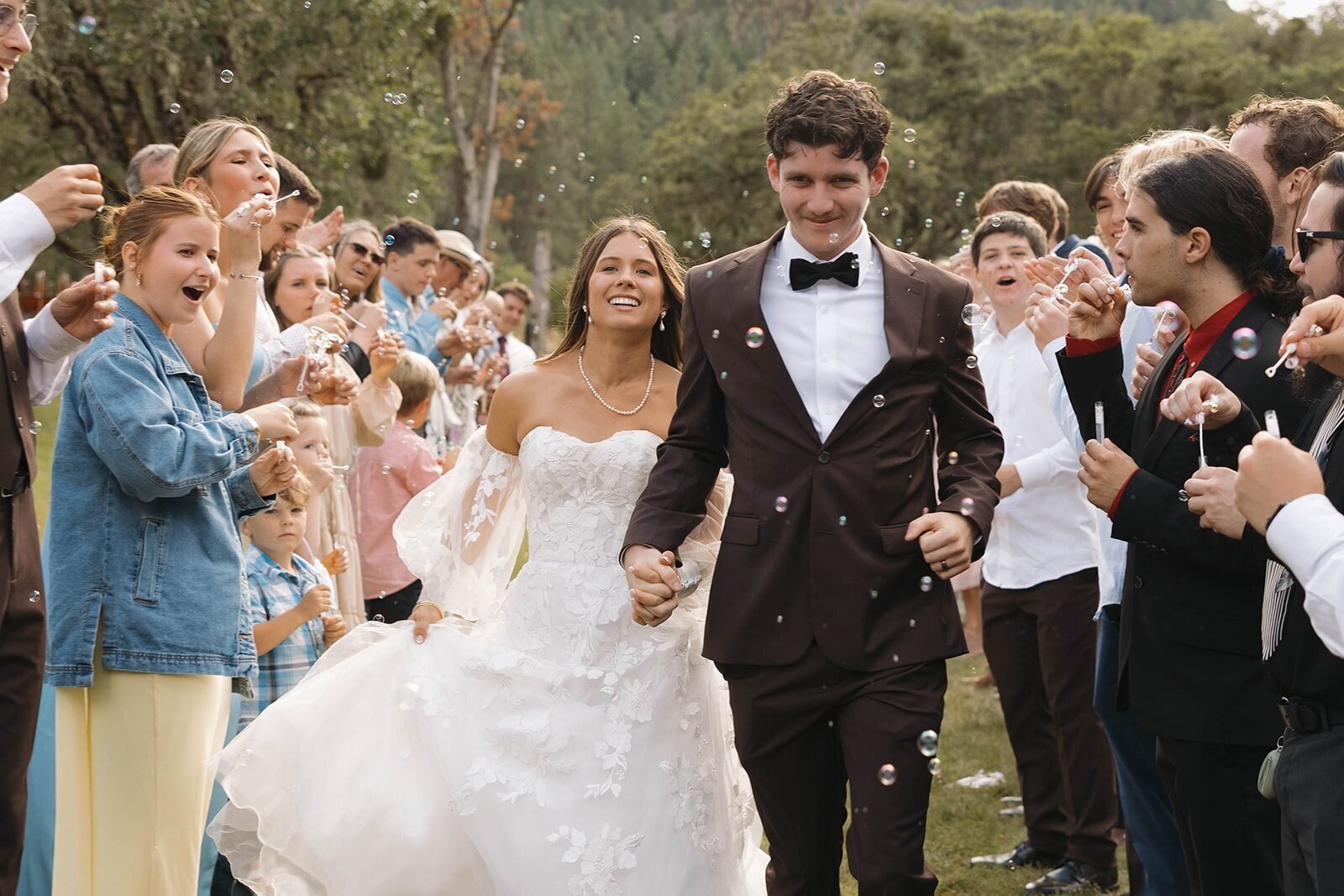 Bride and groom running through a tunnel of guests blowing bubbles