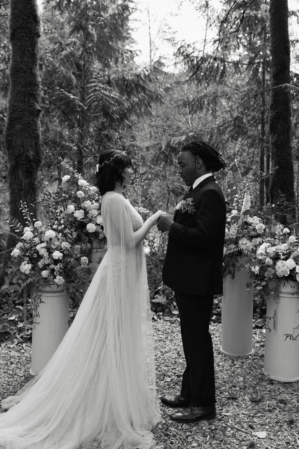 Bride and groom exchanging vows surrounded by floral arrangements