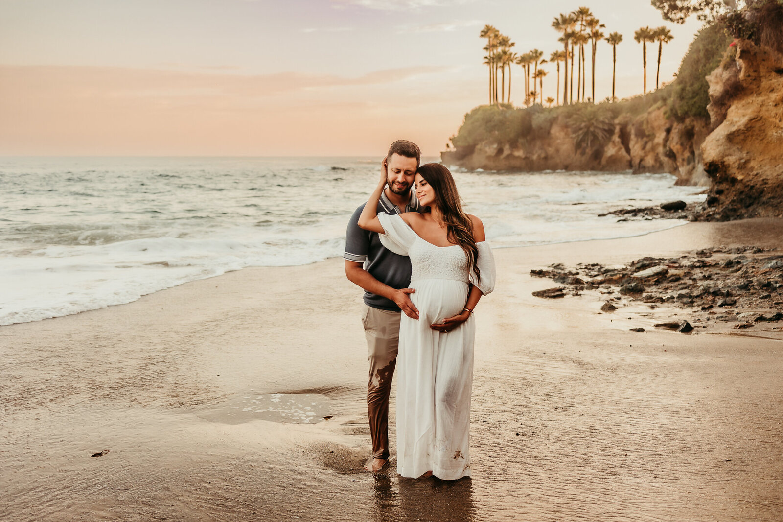 regnant couple holding each other during a golden-hour maternity photoshoot at Laguna Beach, captured by Southern California photographer Brittani Luce

