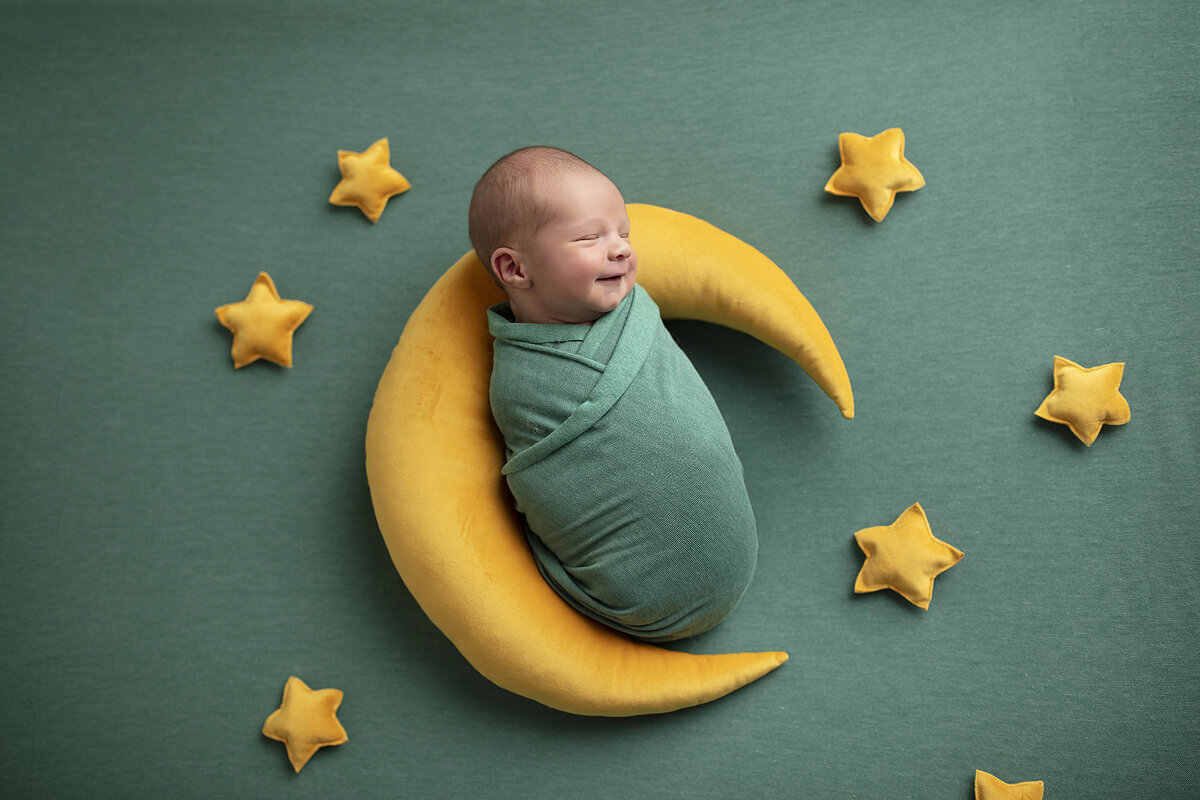 Newborn boy posed with the moon.