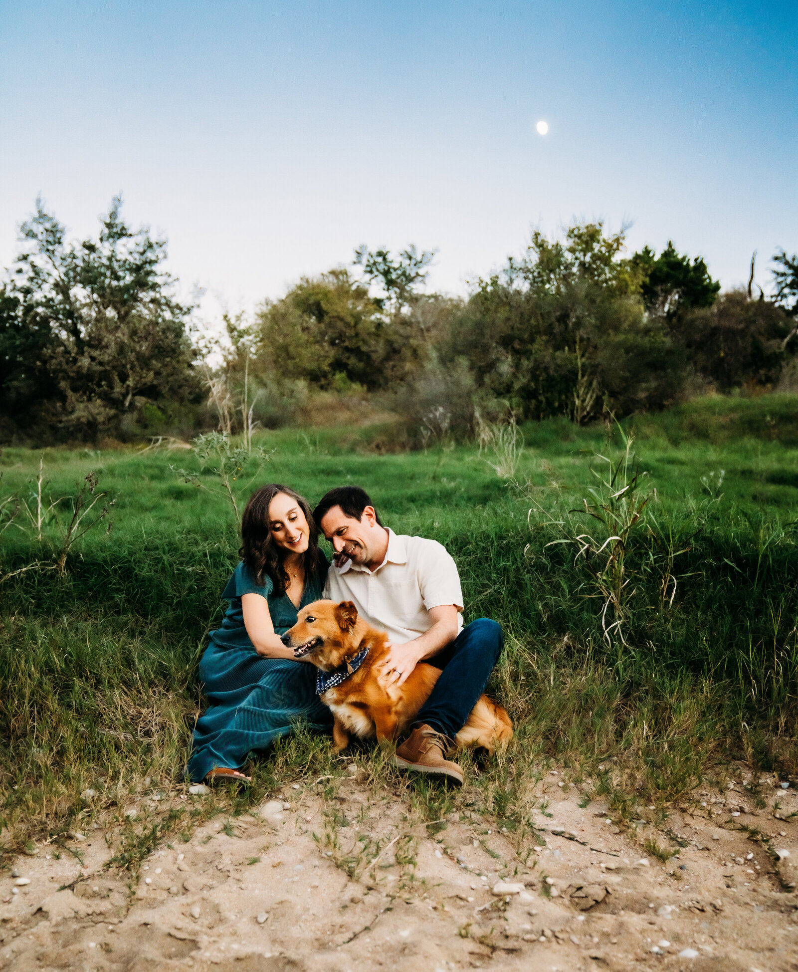 Maternity Photographer, Pregnant woman and her husband sit in the grass and play with their dog, everyone's happy