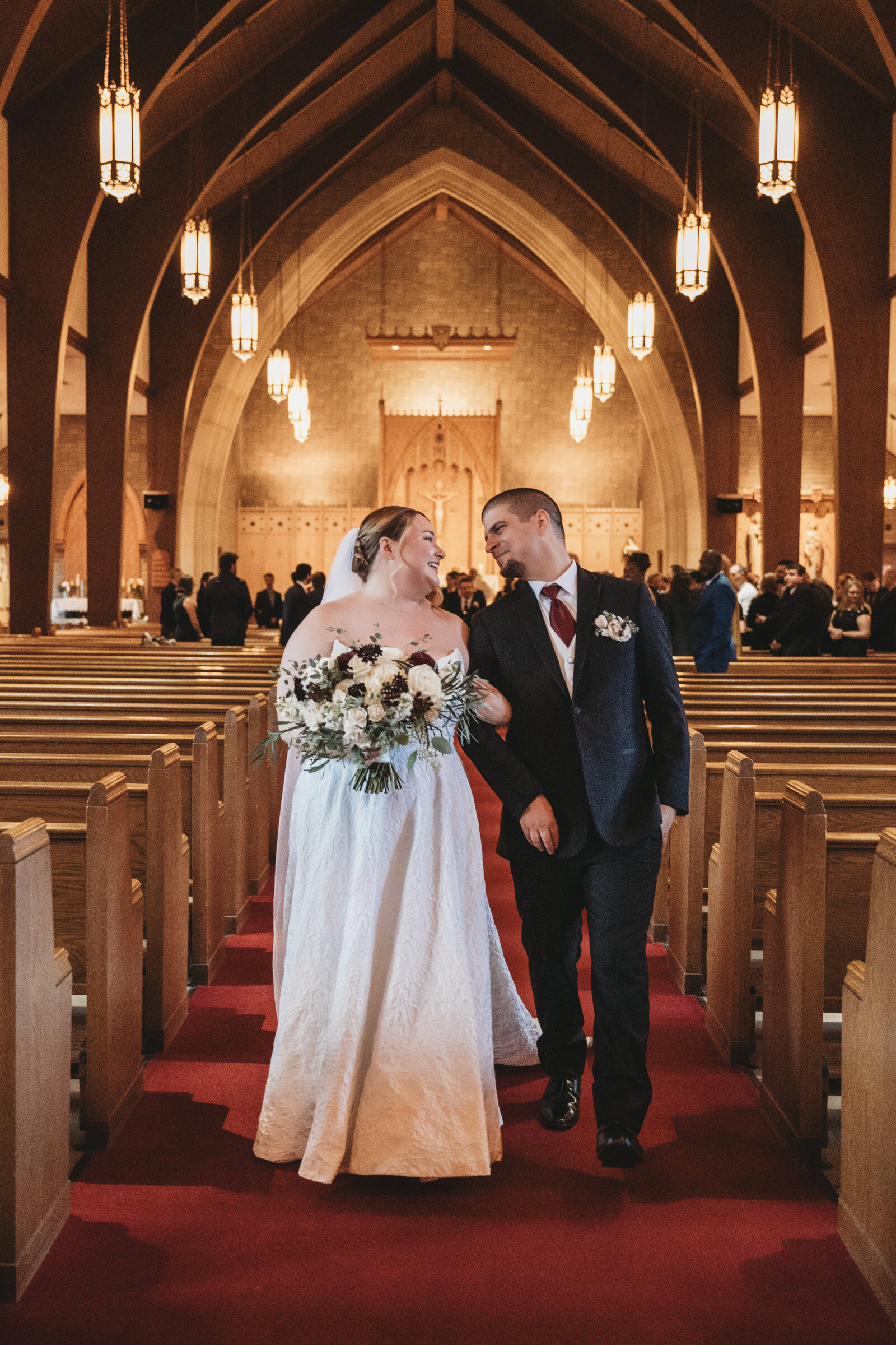 Celebrate the beauty of a timeless church wedding with stunning photography that captures every joyful moment. This radiant newlywed couple walks down the aisle, surrounded by the warm glow of romantic lighting and classic architecture. Perfect for couples looking for Connecticut wedding photography that blends tradition, elegance, and love. Book your wedding photographer today!