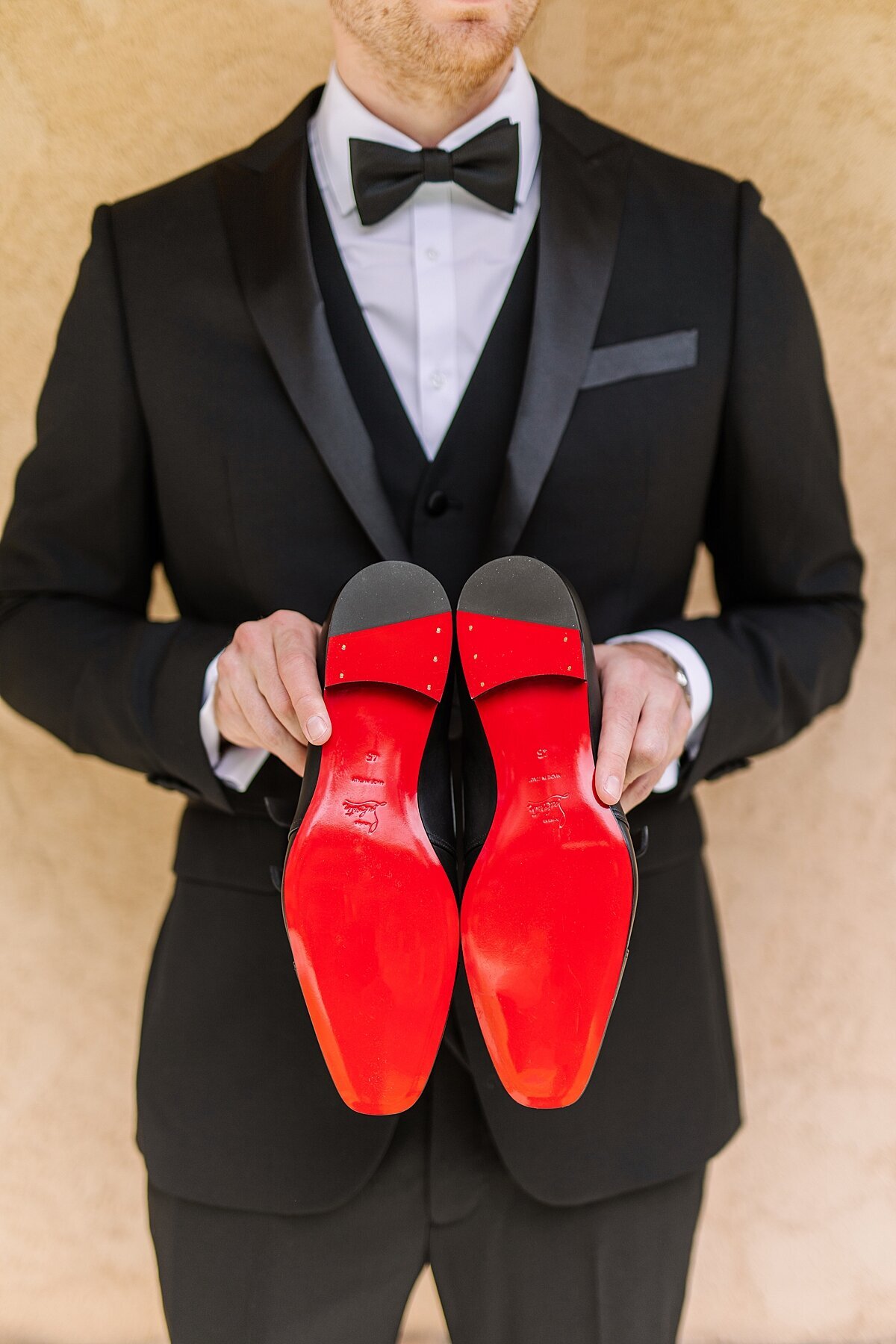 Groom holding Louis Vuitton red-bottom shoes at Los Willows wedding venue.,