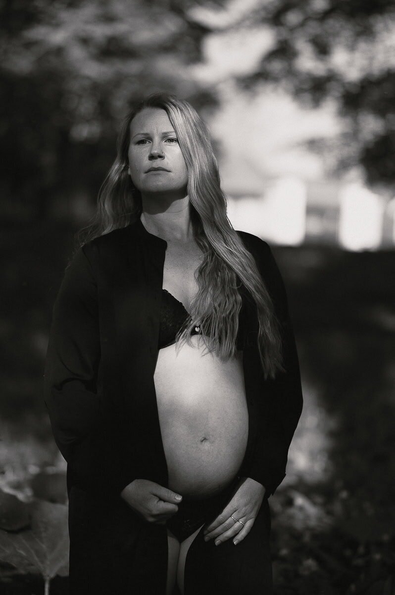 Gravid kvinna blottar sin växande mage i svartvit bild.