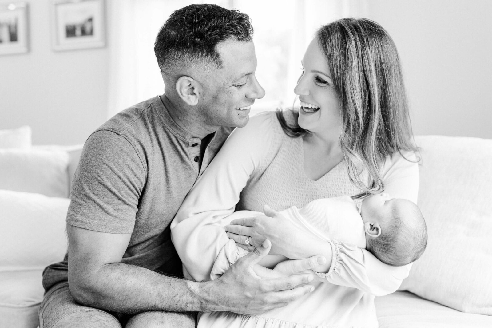 Black and white image of parents laughing together over their baby