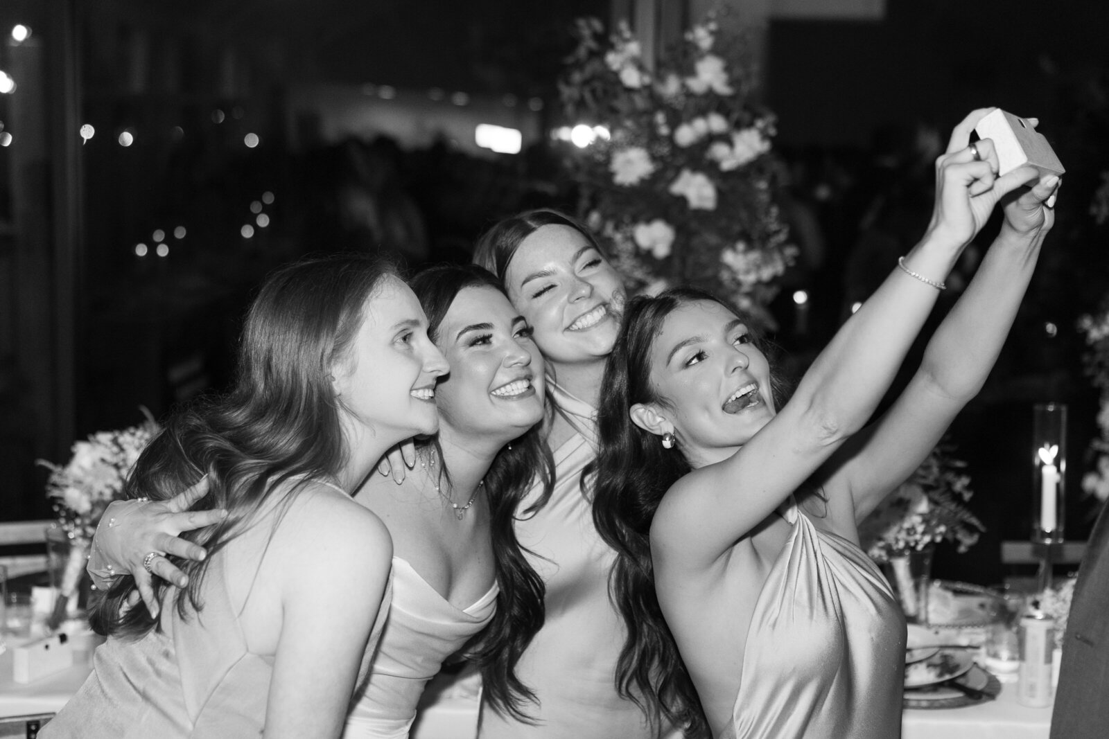 Couple popping champagne during their wedding reception, laughing with friends and family