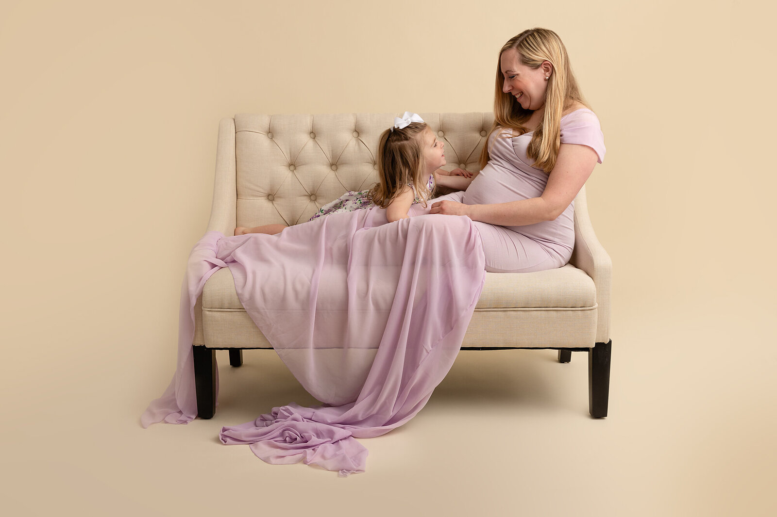 studio portrait of mom and little girl on couch by PHILADELPHIA MATERNITY PHOTOGRAPHER