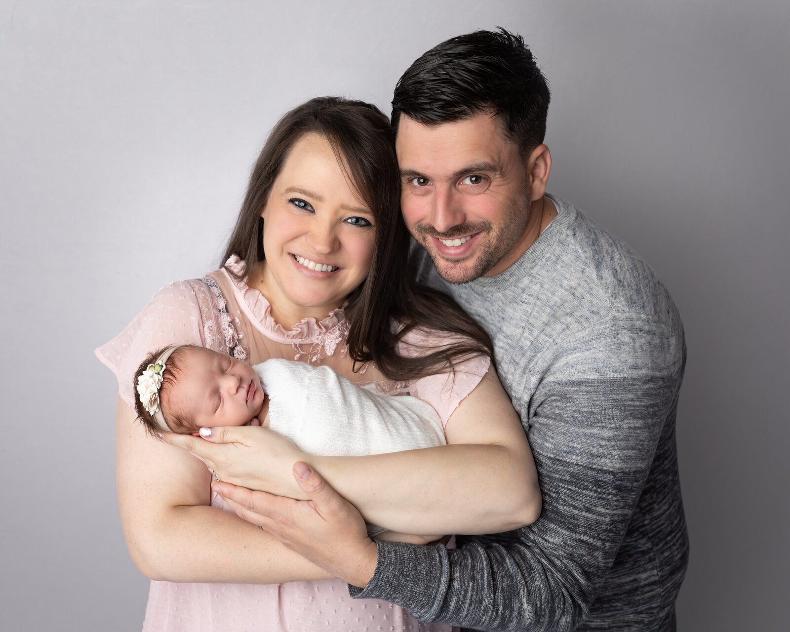 mom and dad holding newborn baby girl for studio portrait