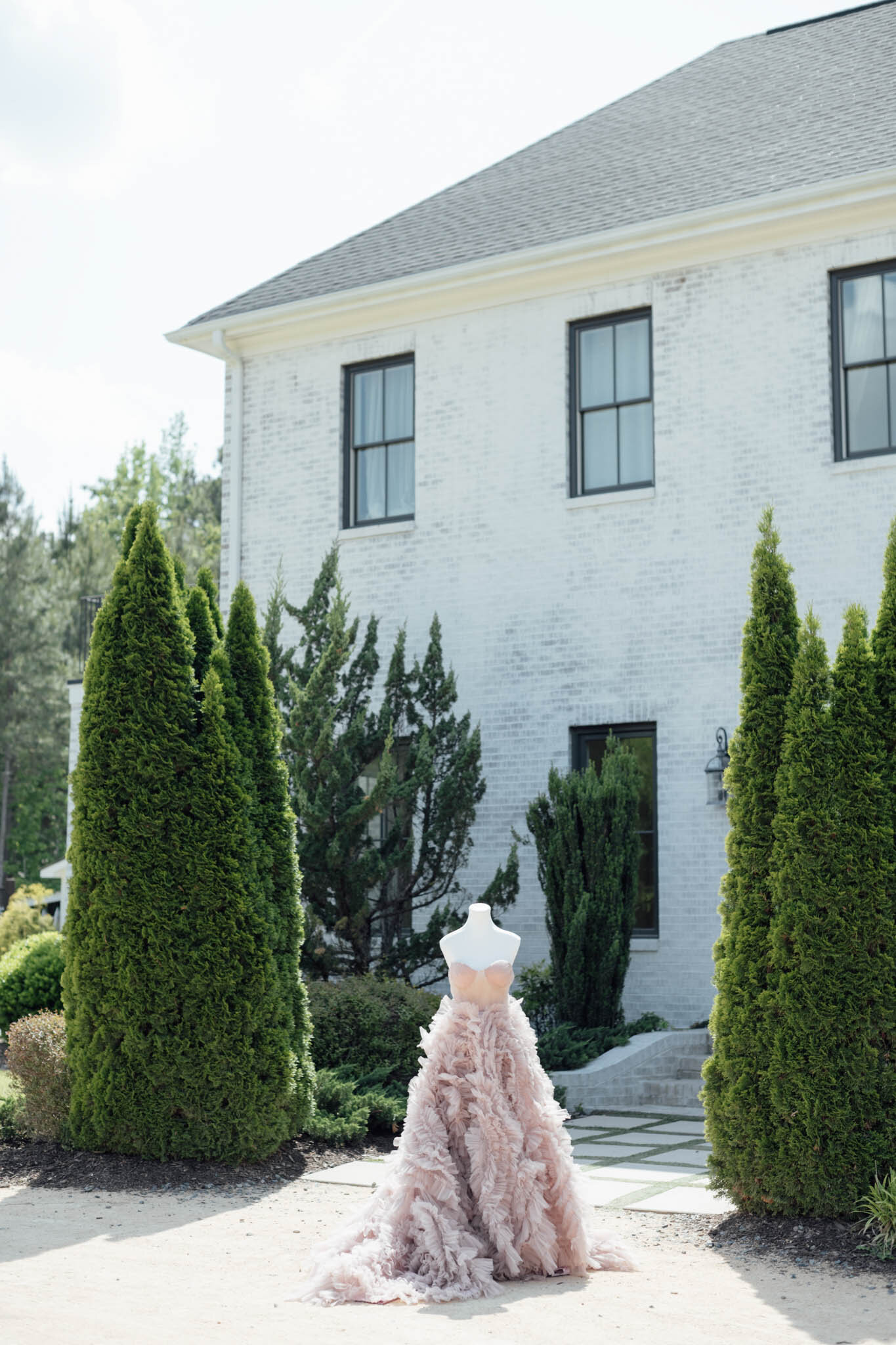 Pink ruffled gown on mannequin outside white venue