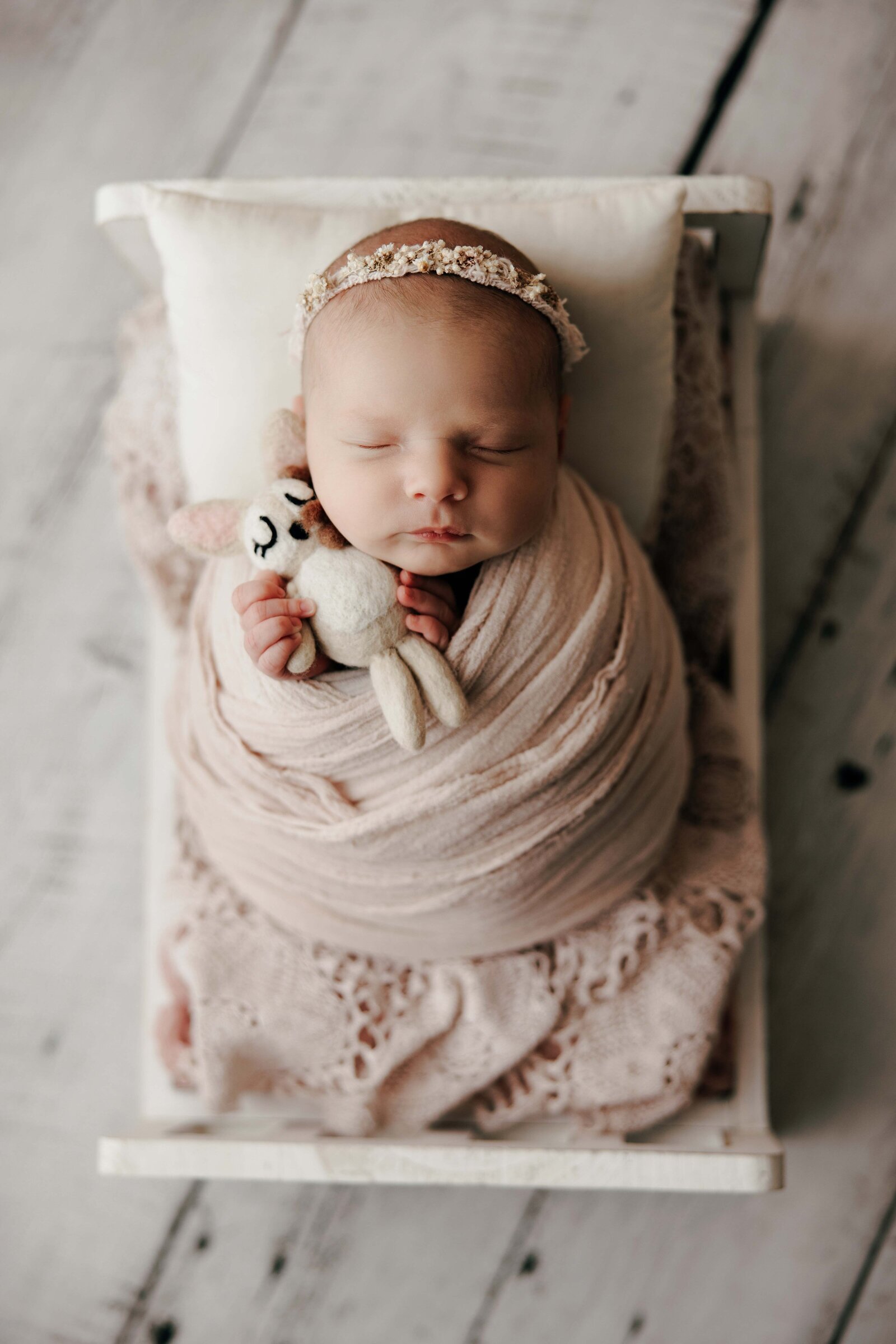 A newborn baby girl holds  a stuffed deer