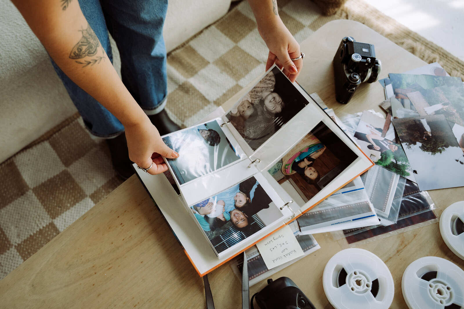 Documentary wedding photographer holding canon camera, surrounded by wedding photographs and cameras