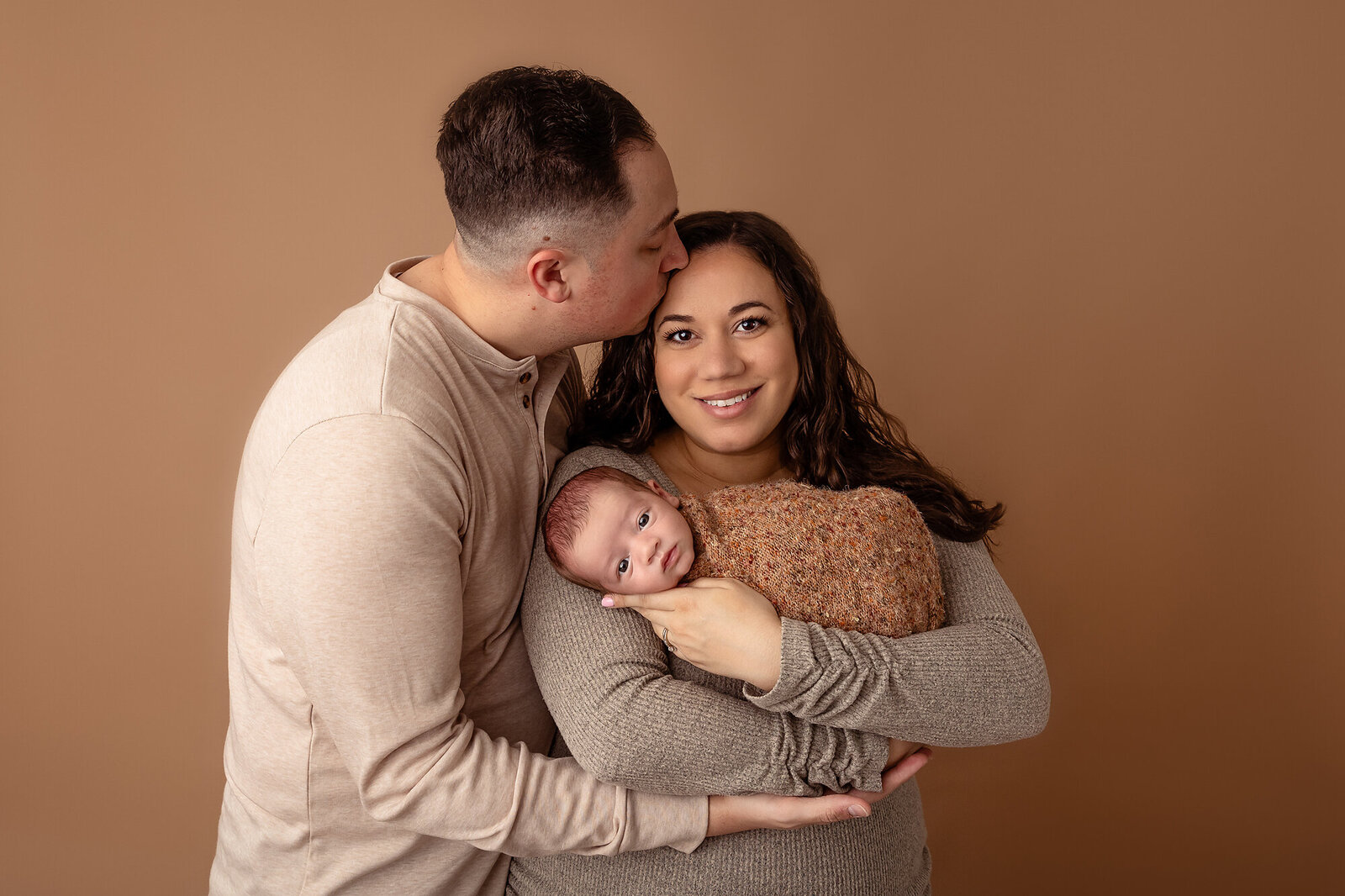dad kissing mom holding baby by Newborn Photography Bucks County PA