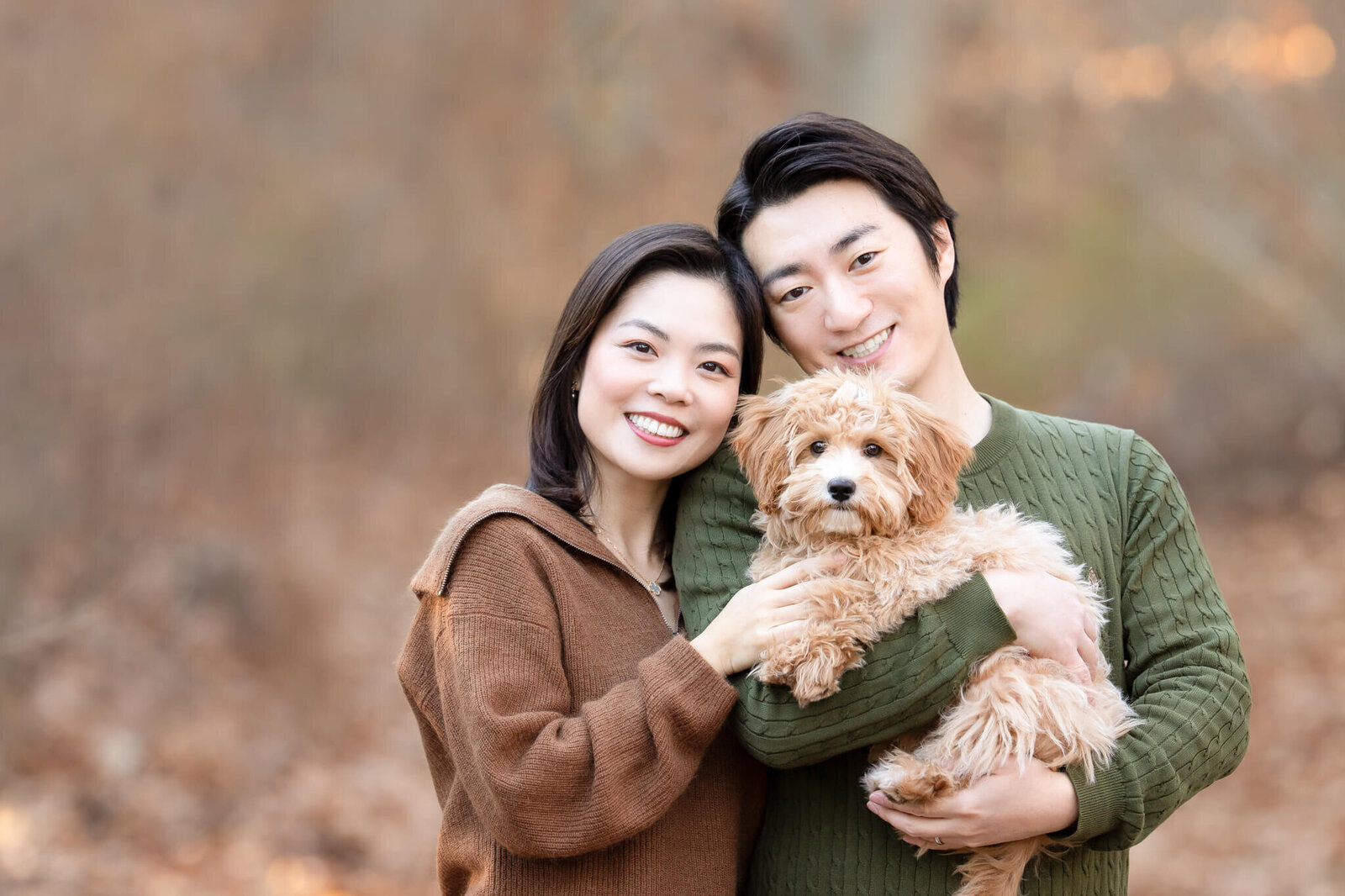 Golden Doodle puppy being held by his gorgeous Asian parents