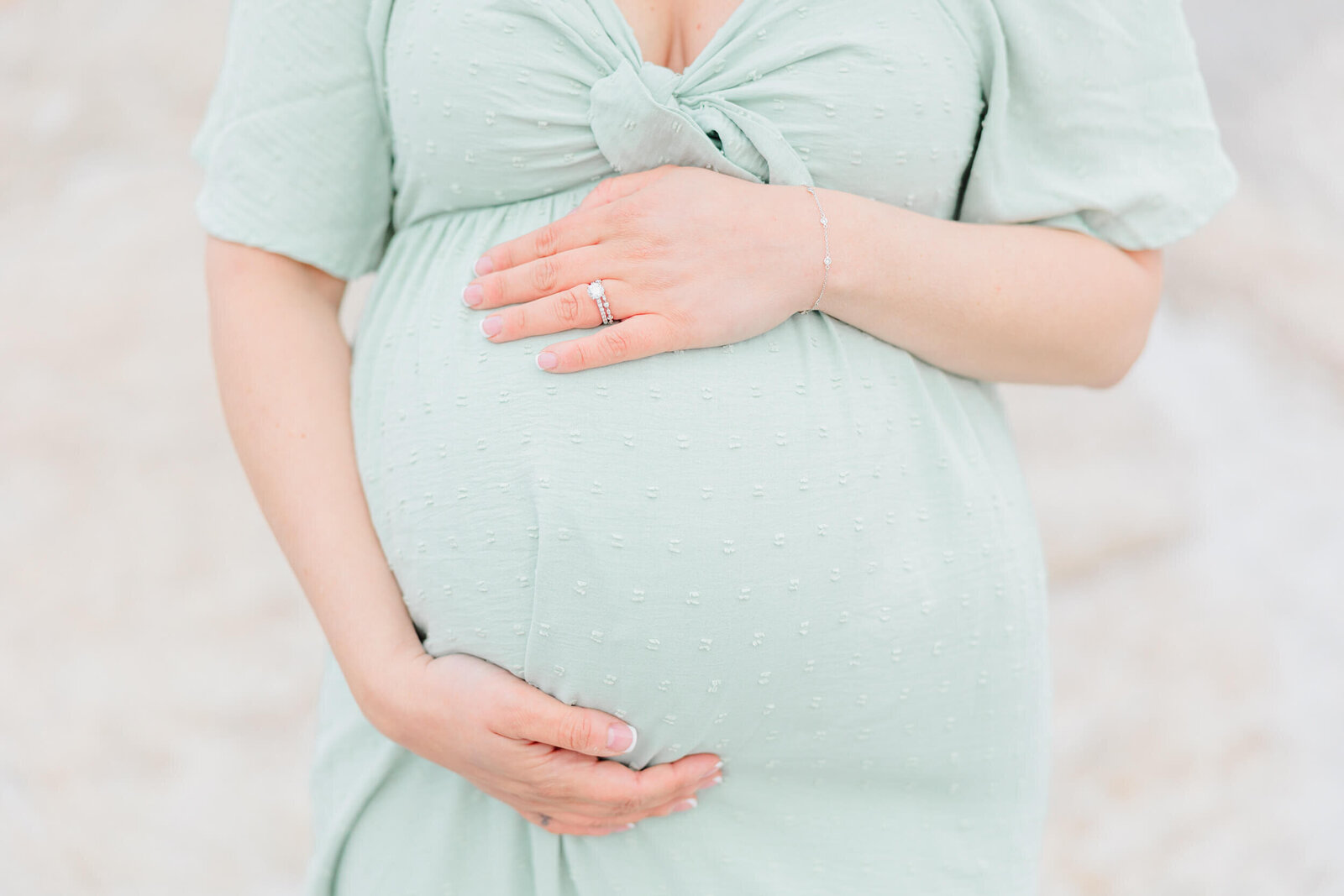 Closeup of a pregnant woman's baby bump cradled by her hands