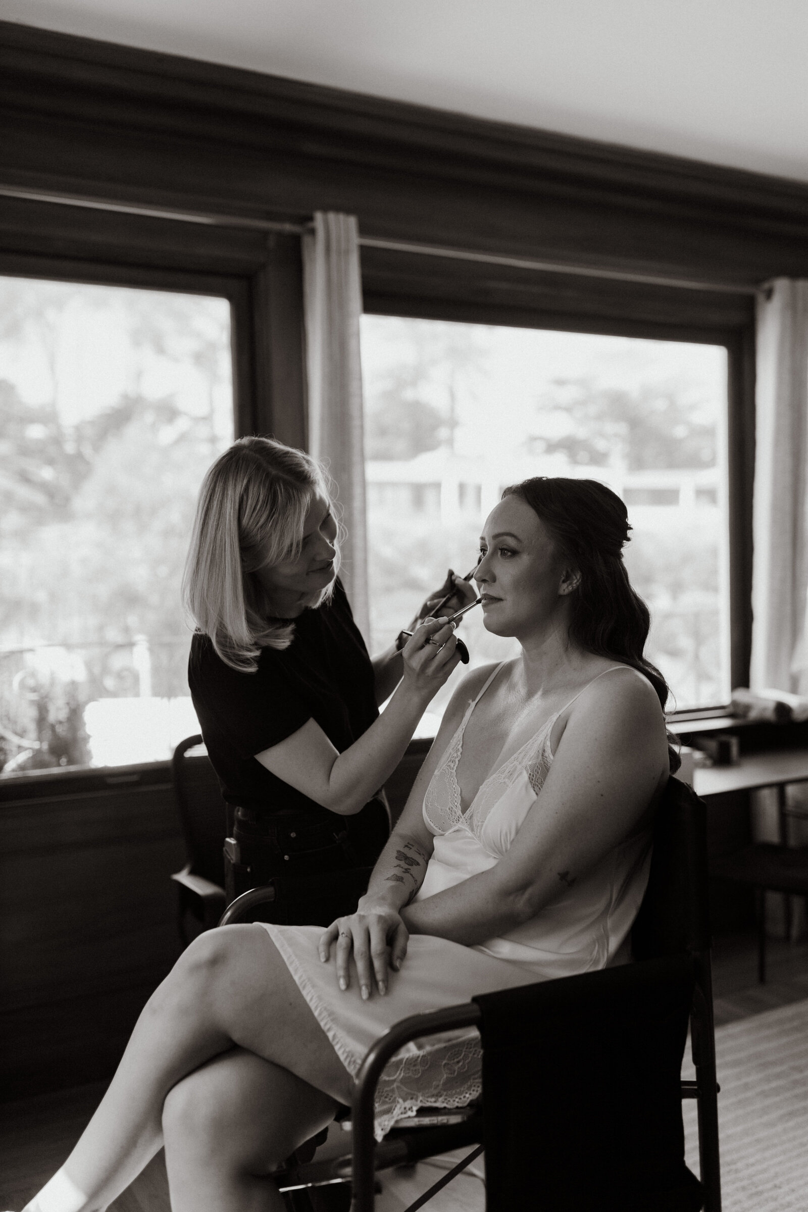 A picture of Yana, the hair and makeup artist doing final touches on a beautiful San francisco bride in California 