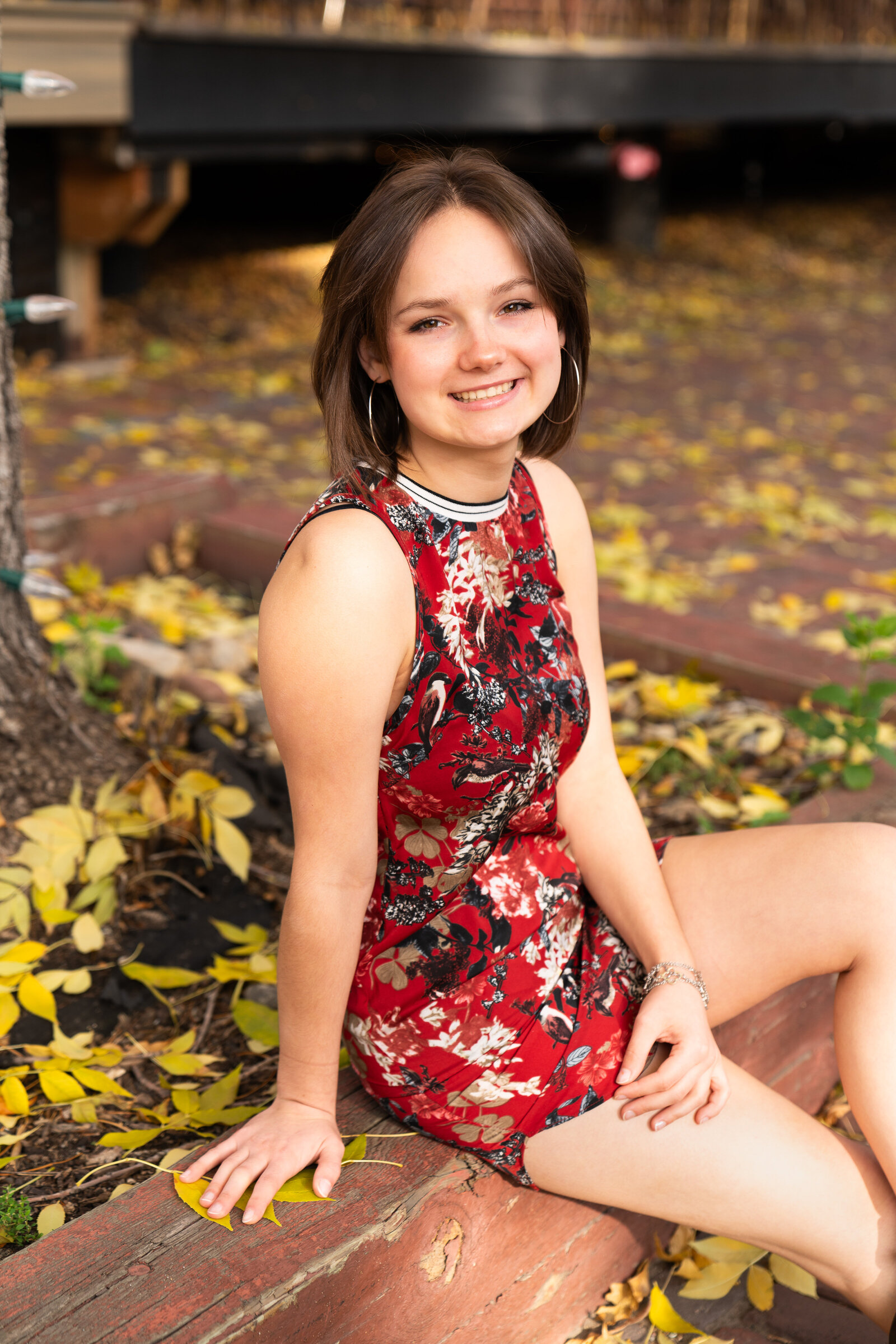 Girl sits and smiles at the camera for her fall senior pictures in Minneapolis, Minnesota.
