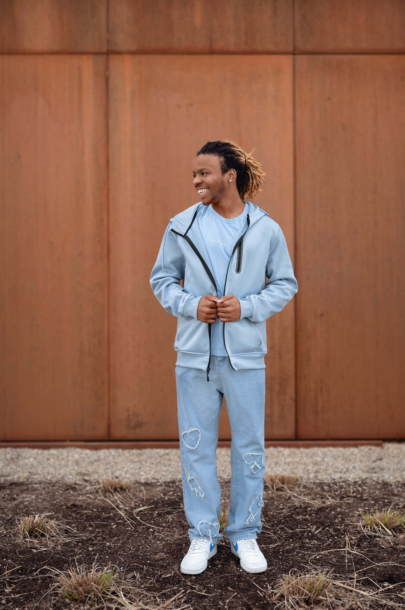 High school senior guy holding onto his jacket looking to the side