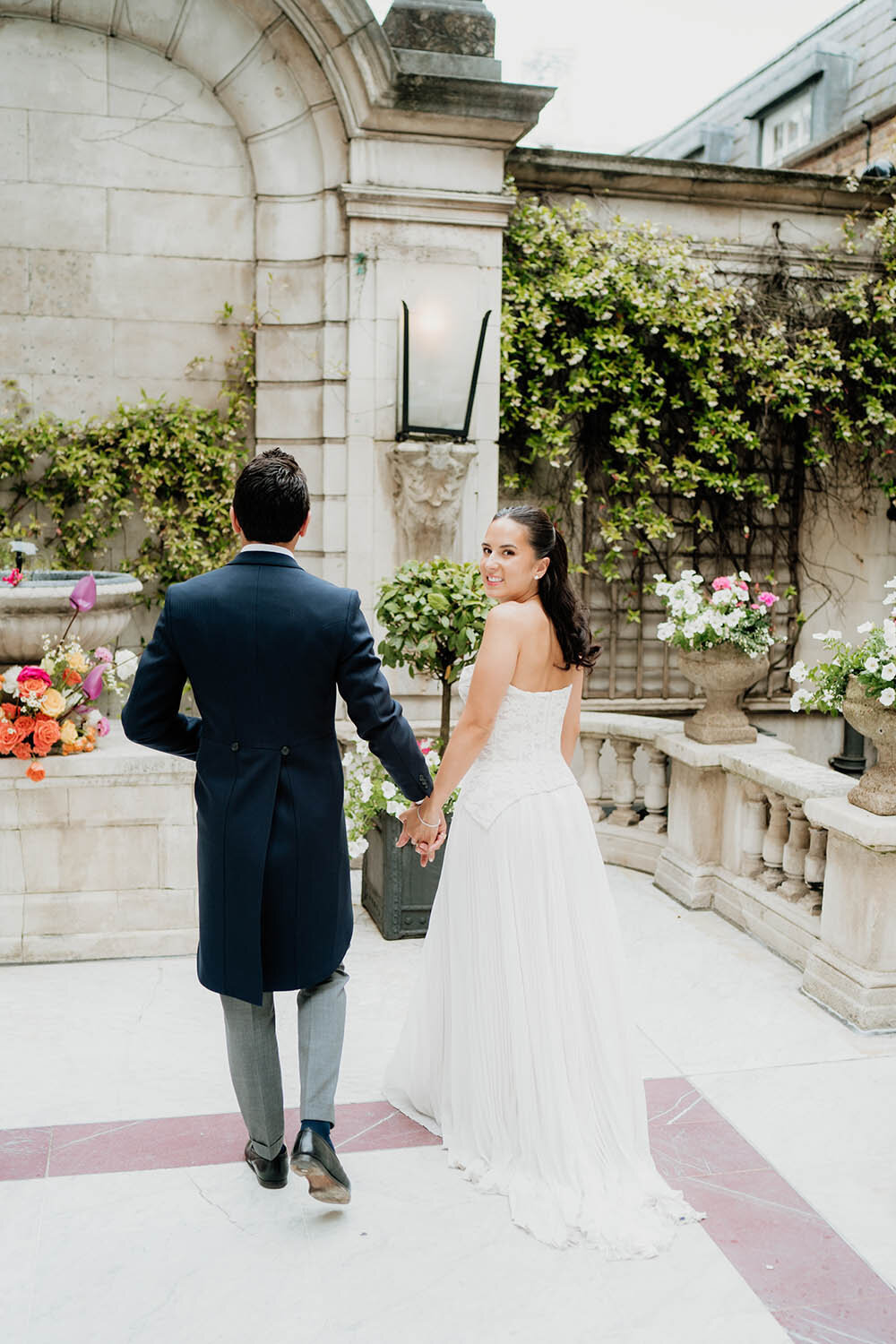 modern wedding photo of a bride and groom walking at dartmouth house courtyard with bride looking above her shoulder
