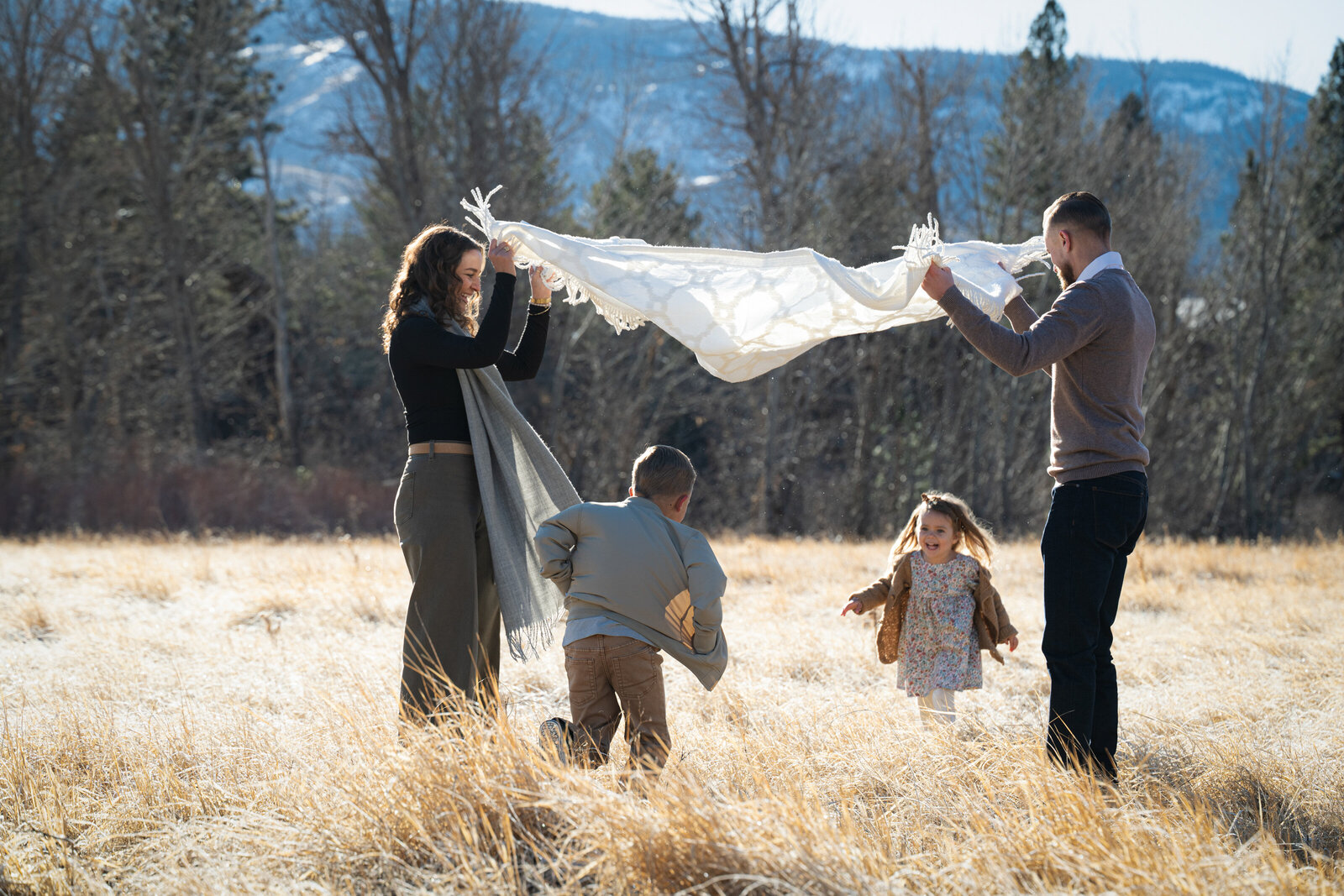 children running under a blanket held by their parents in a golden verdi nevada field
