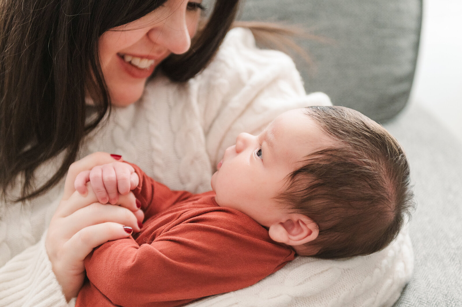 mother looking down at newborn in orange onsie at home by york pa newborn photographer