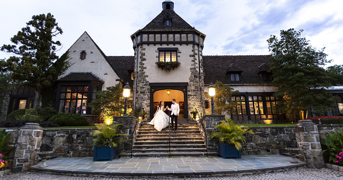 bride and groom walking down the front stairs of the Pleasantdale Chateau in NJ