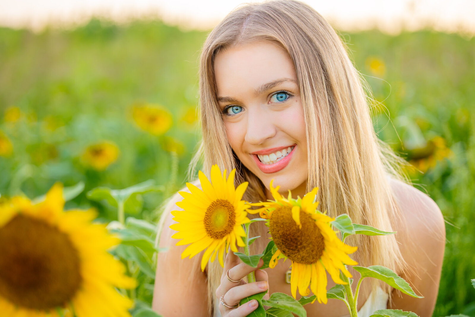 senior holding sunflowers in hands and smiling in St. Louis MO