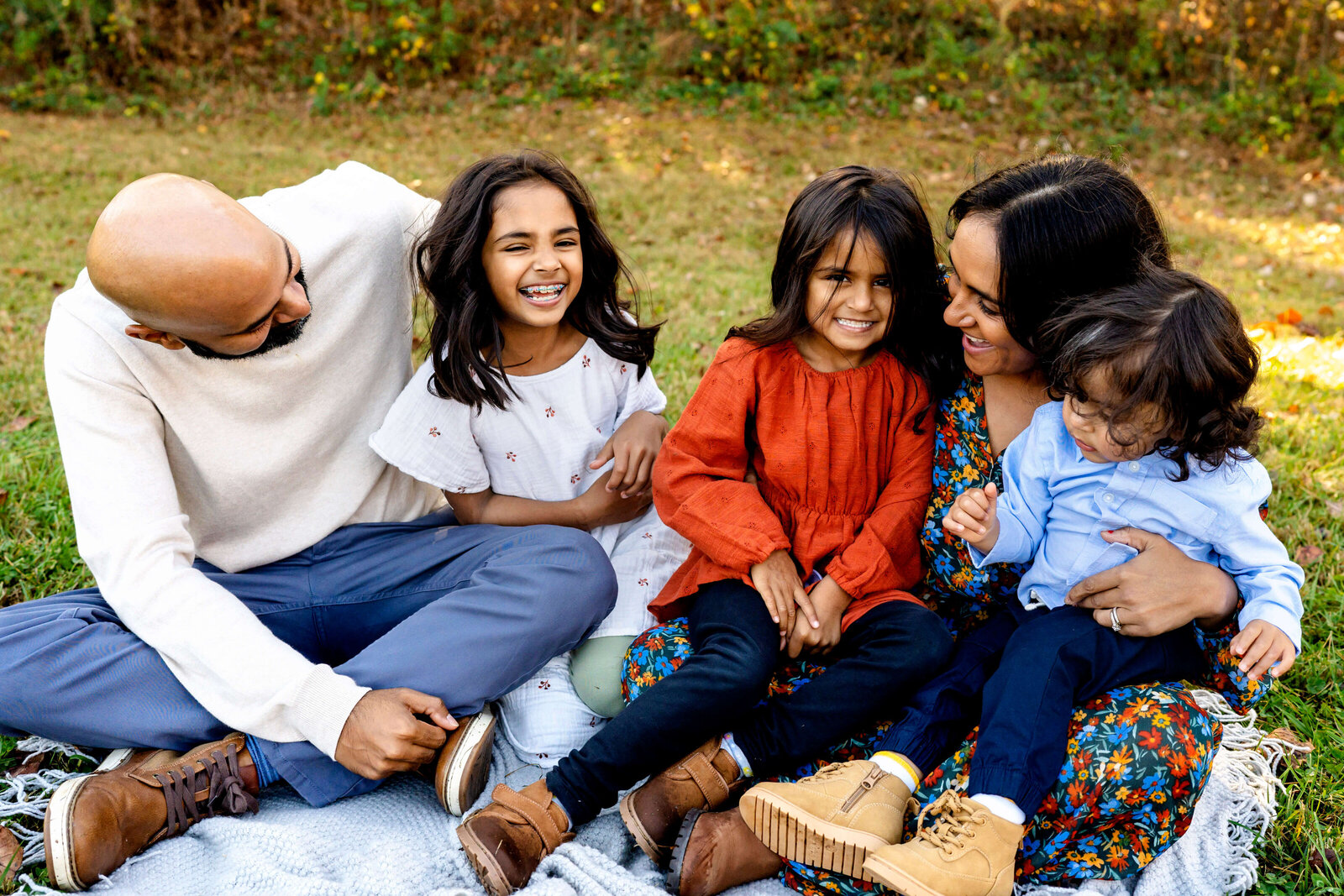 Family Photography sessions in Atlanta, Family of 5 sitting outside on a blanket smiling at each other