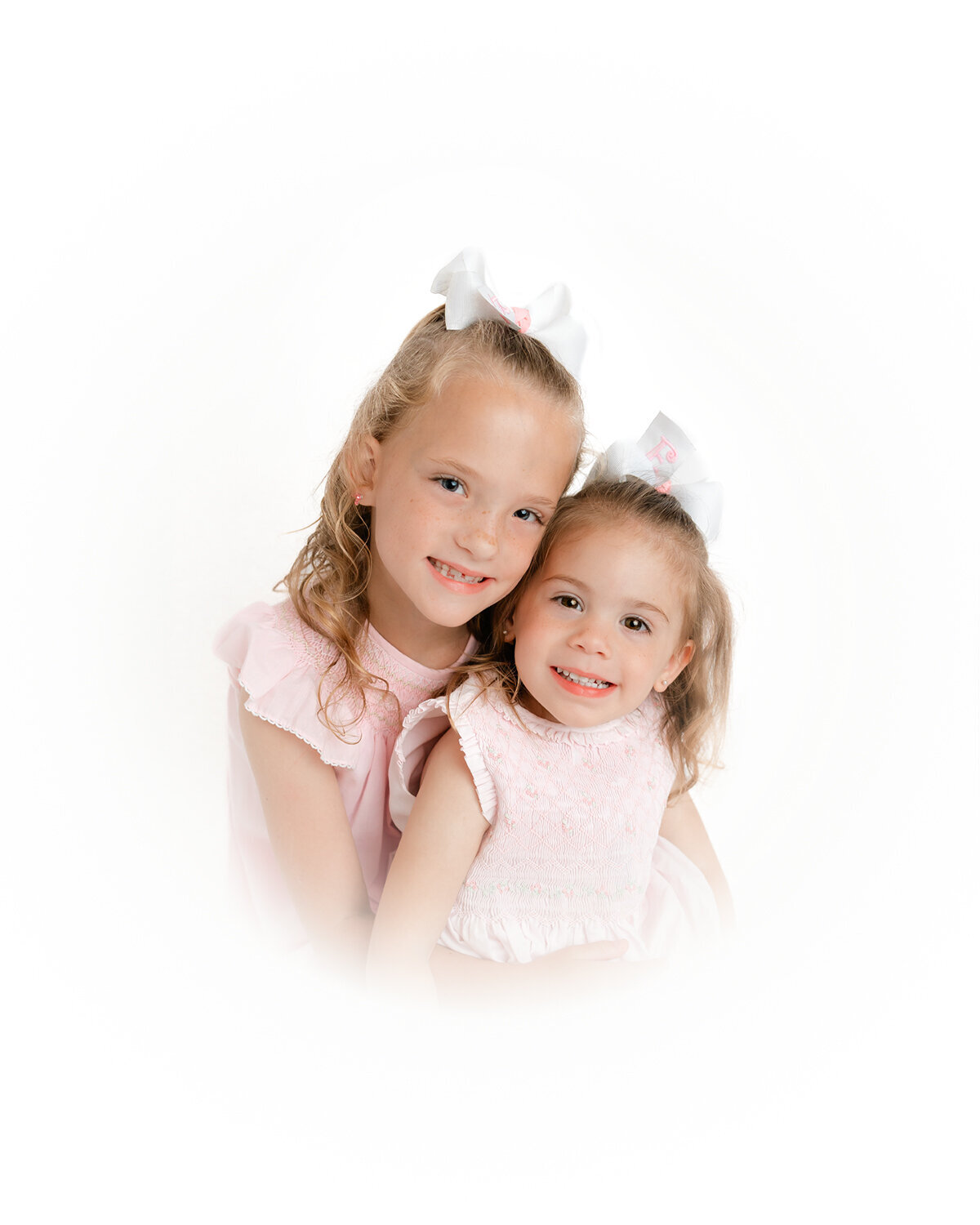 Sisters wearing pink smiling at the camera for their classic heirloom portraits in Savannah, Ga with Constance Calton Photography