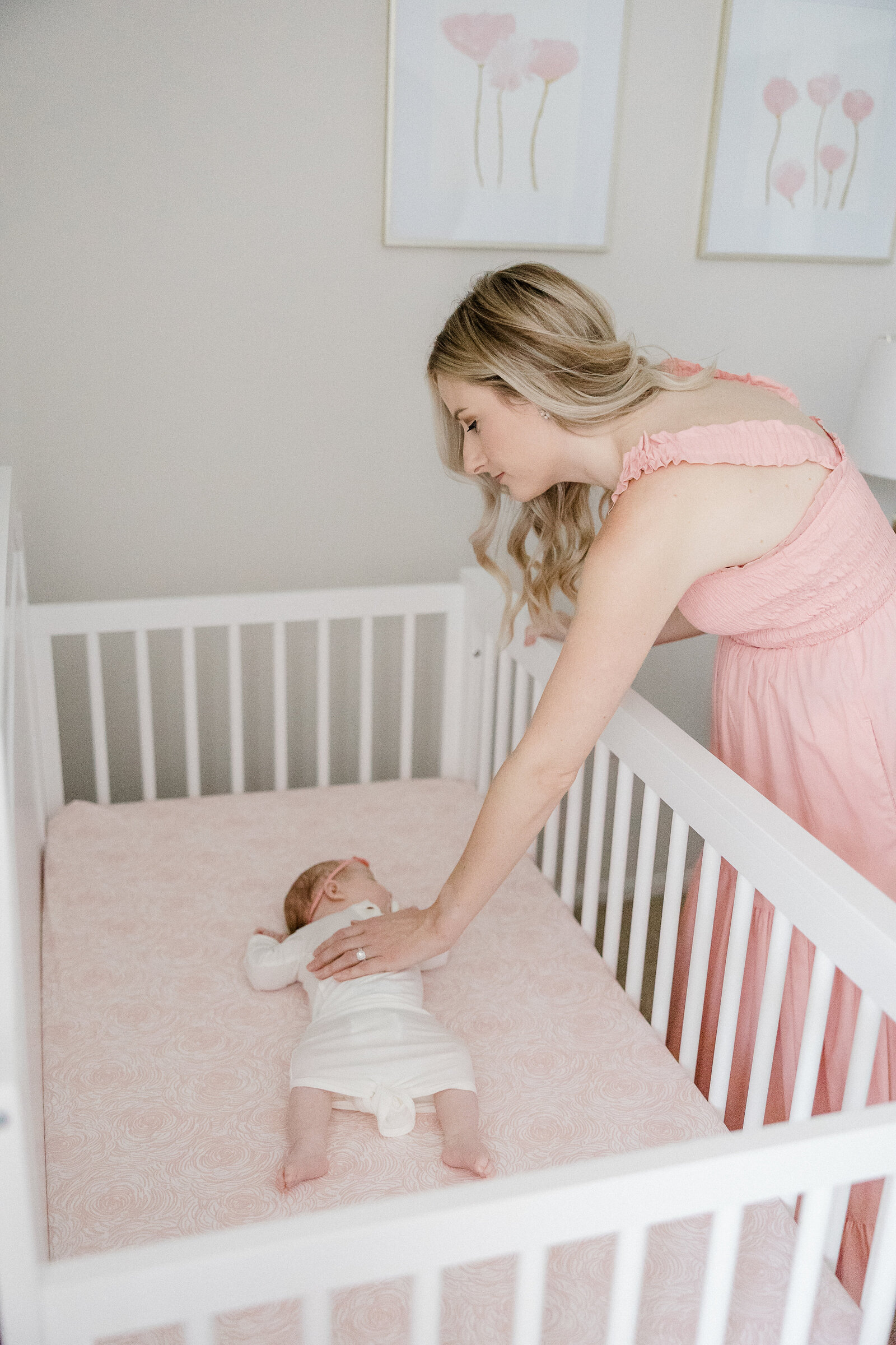 new mom reaching to pick up baby in crib
