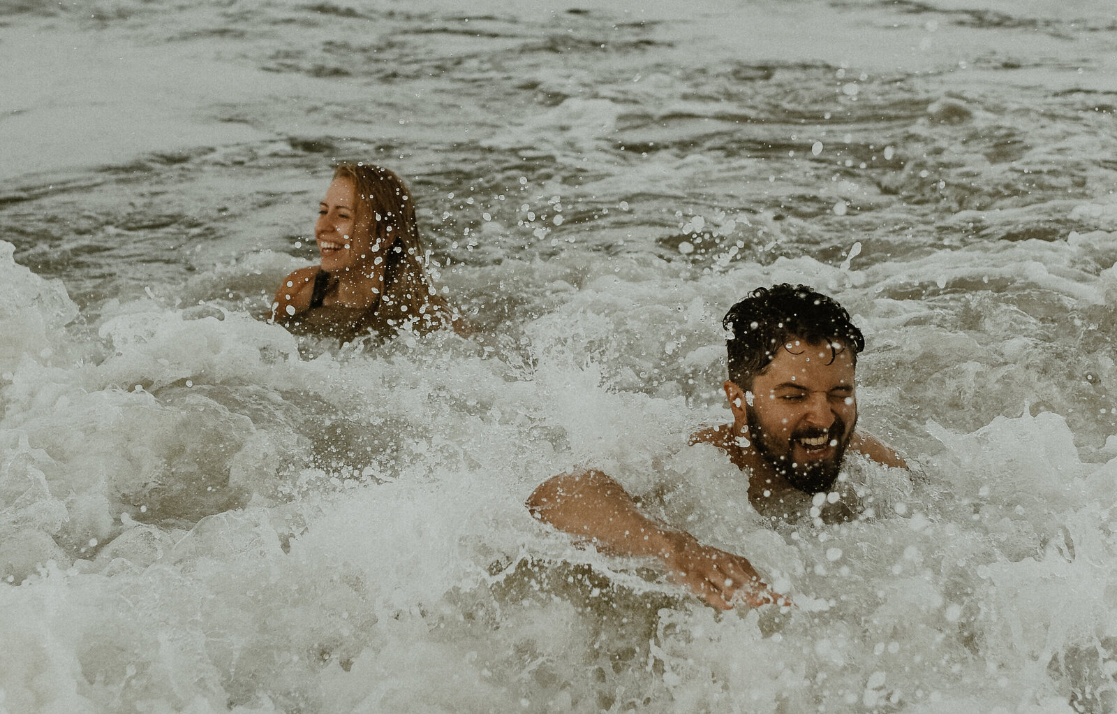 A couple playing in ocean waves in Charleston South Carolina at Folley Beach.