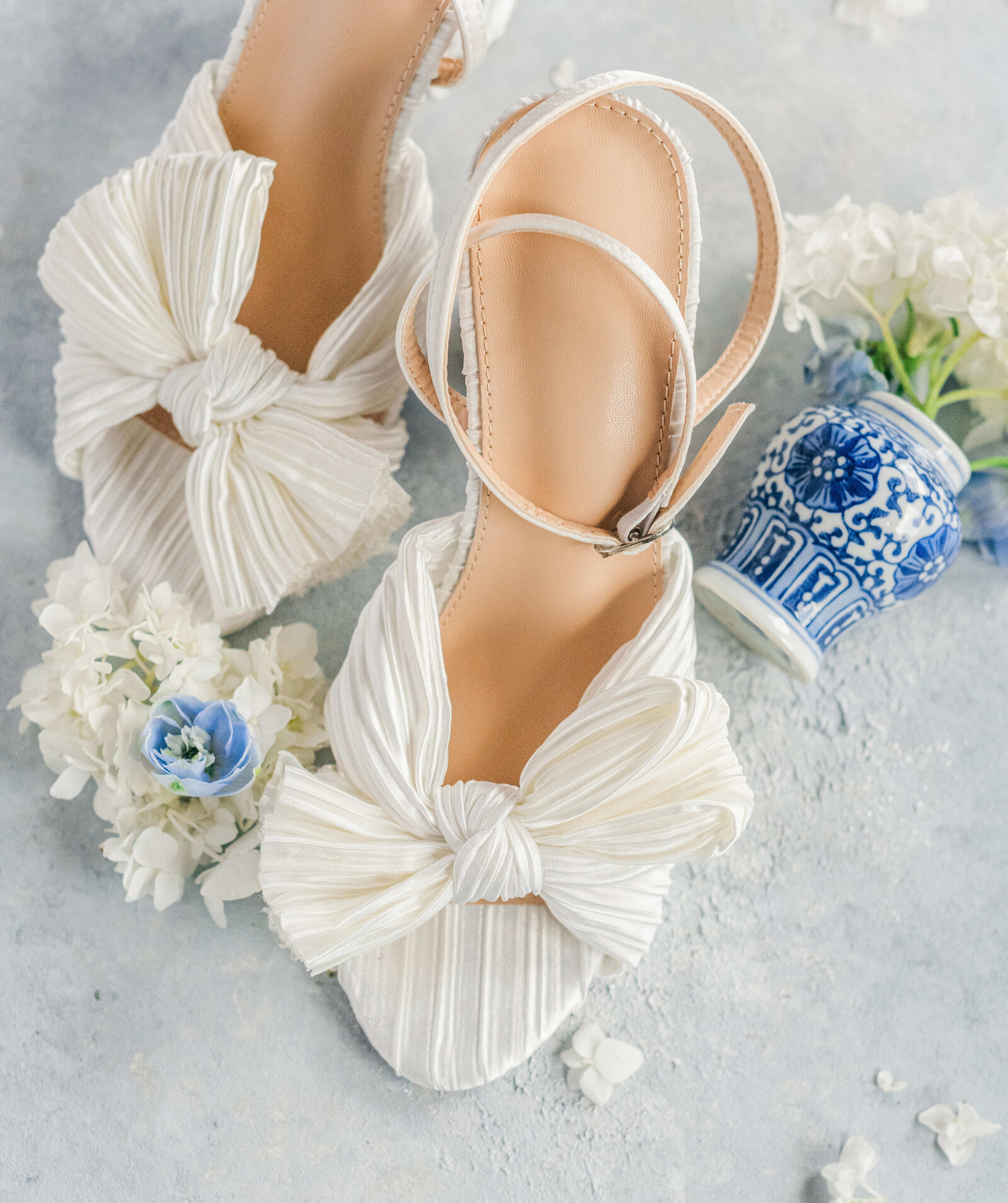 White bridal shoes on a light blue background curated for bride detail flatlay photos