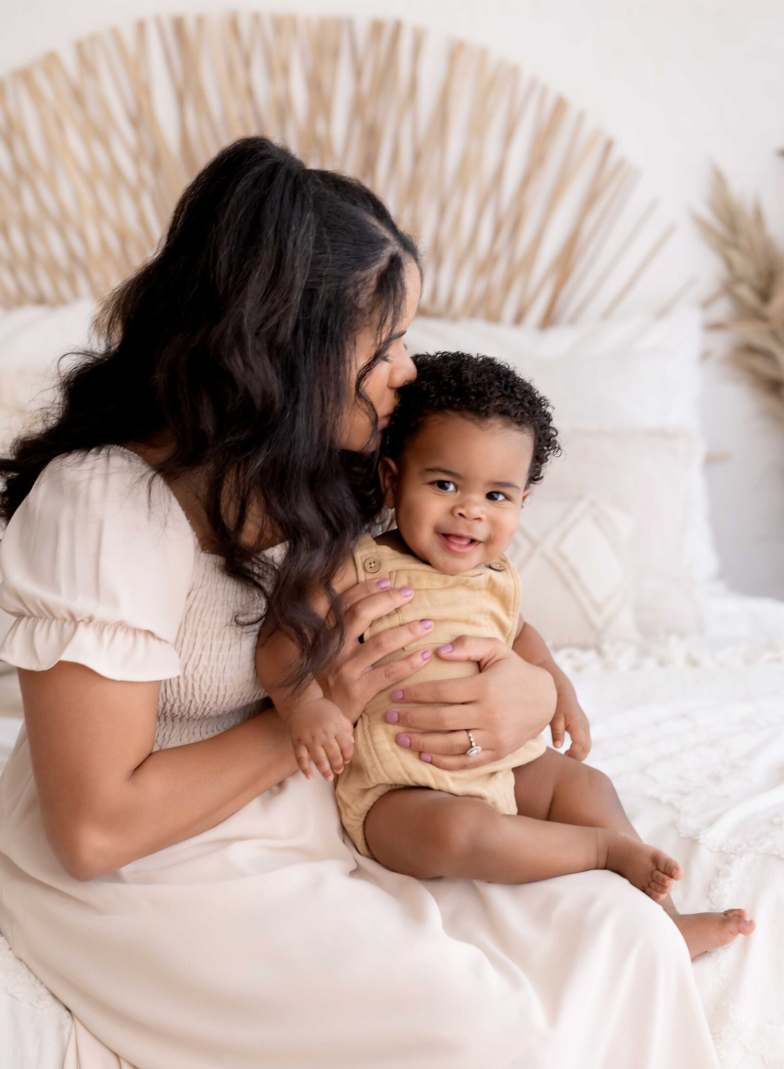 Mom kissing baby on bed in a boho bedroom setting. 1st Birthday photo taken by Jenni Nikki in Atlanta, GA