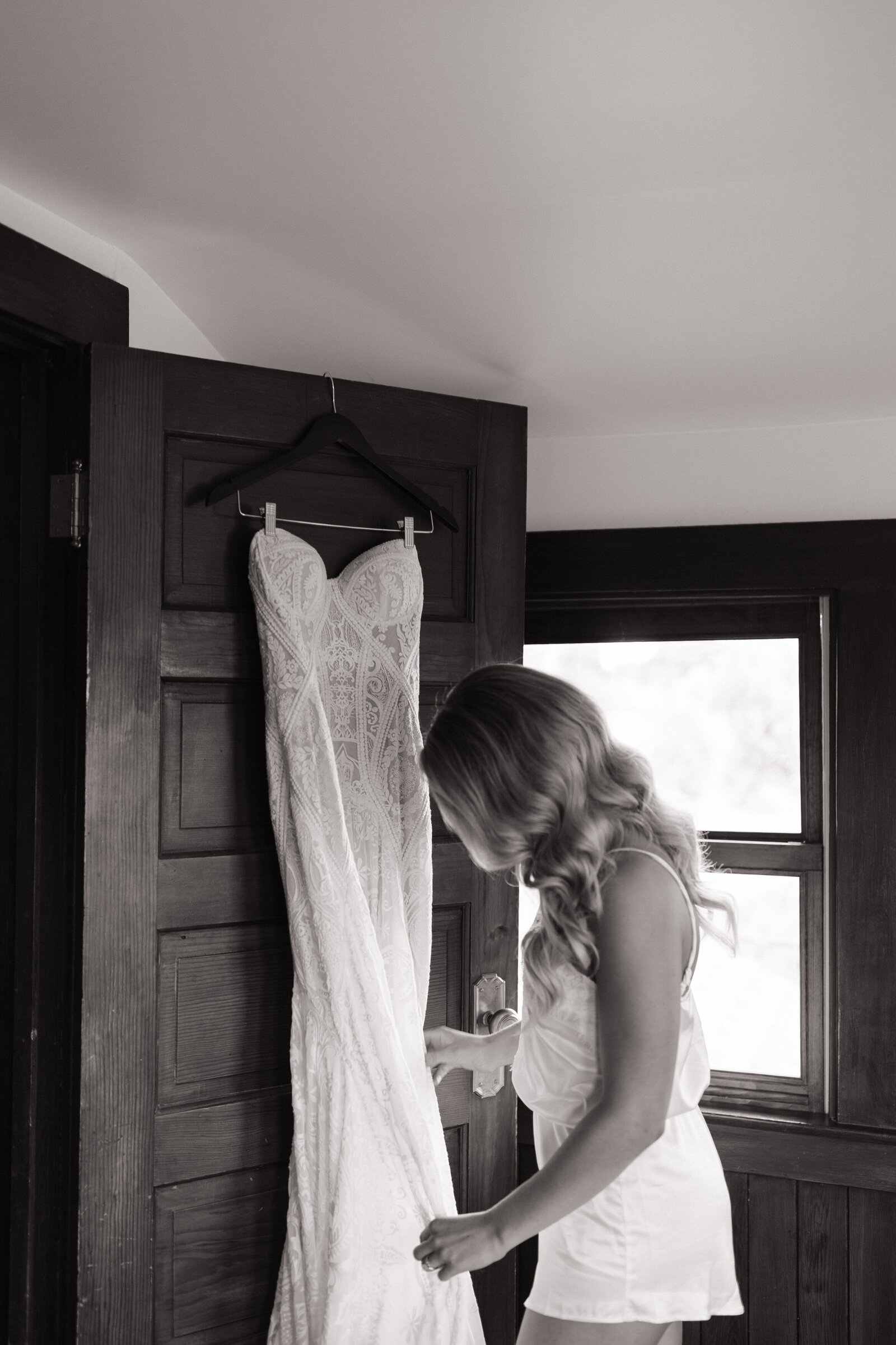 Bride smiling while adjusting her lace dress in the bridal suite before the ceremony in Idaho