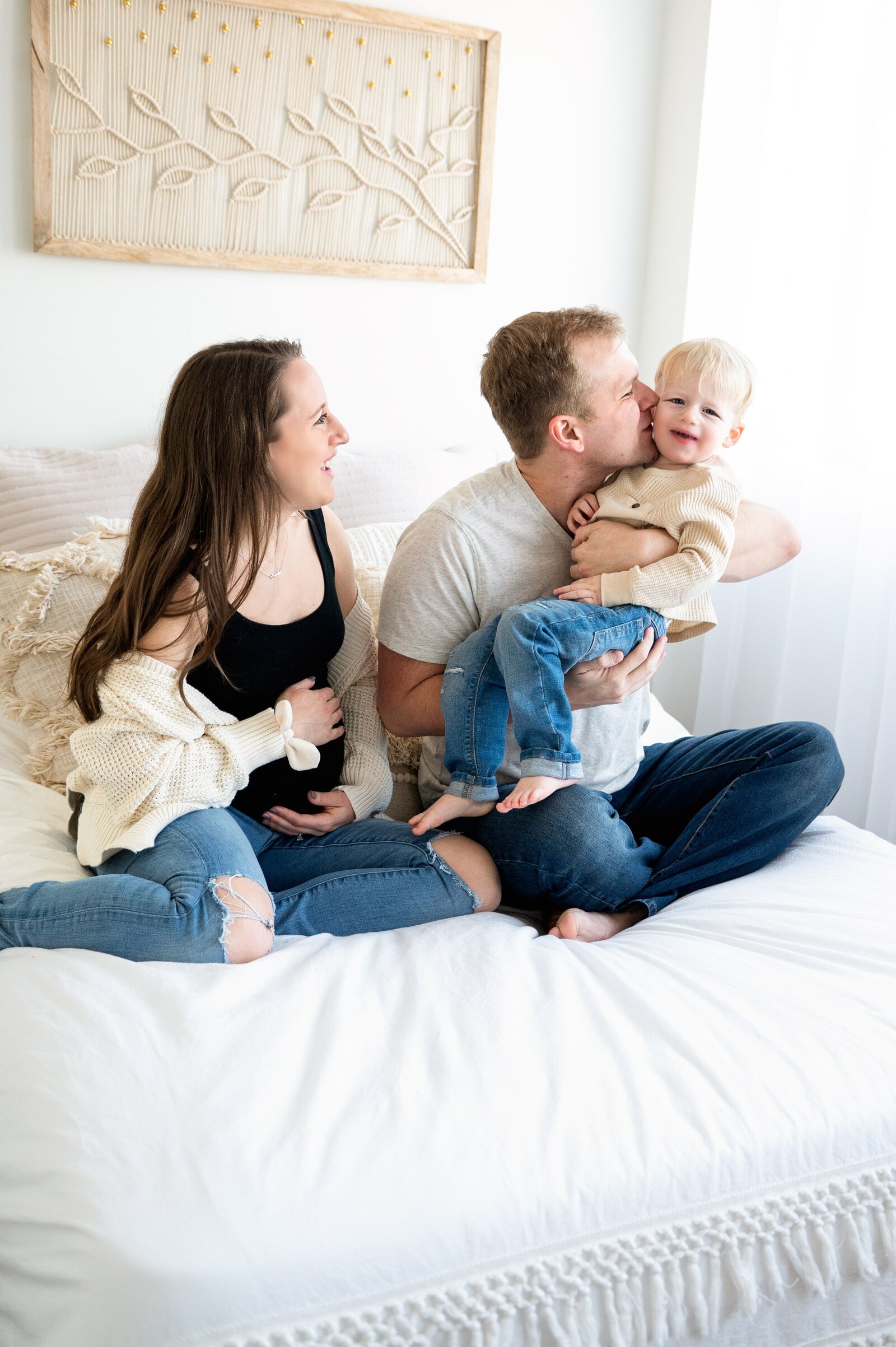 family sitting on bed playing with son