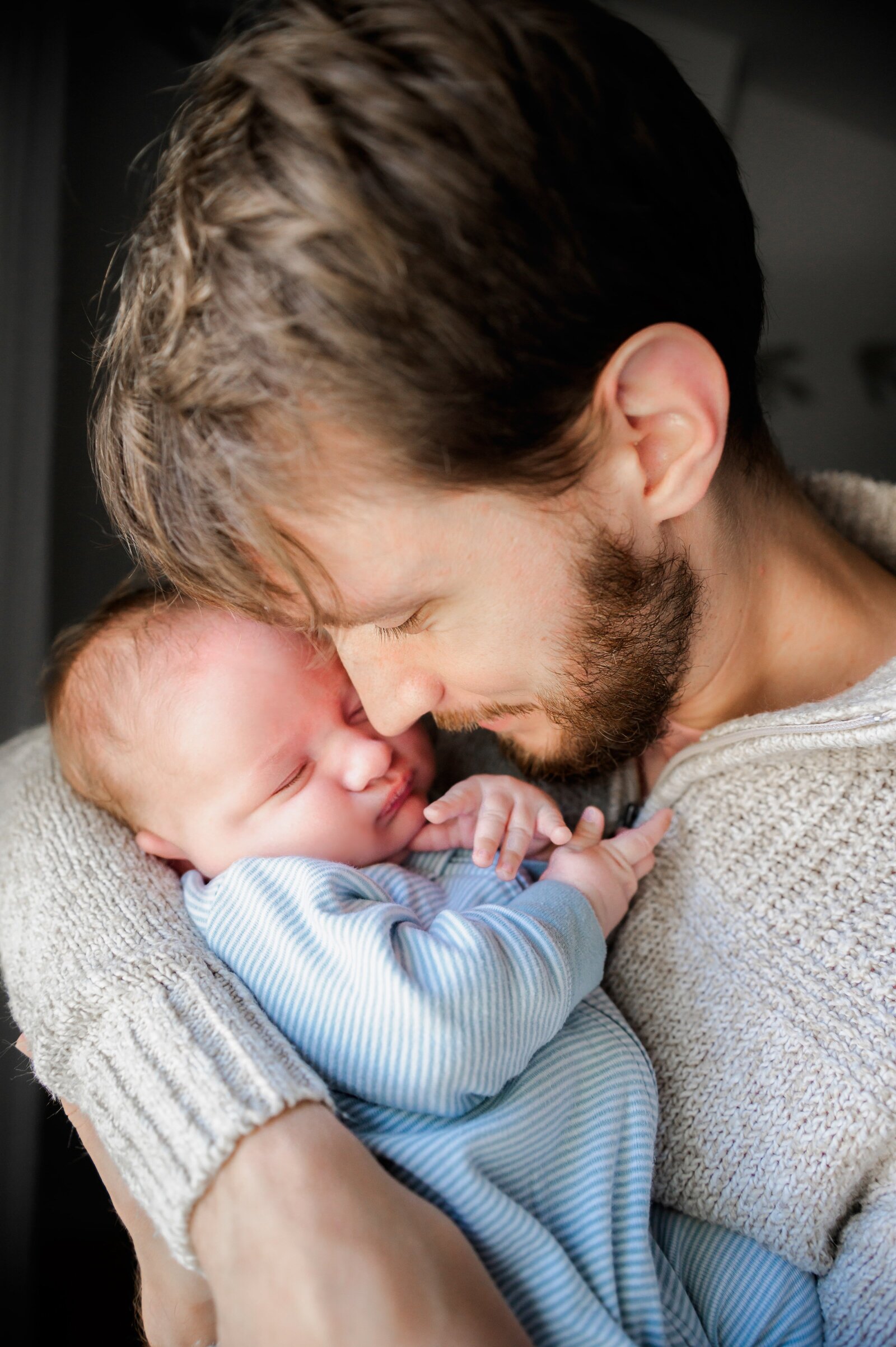 dad snuggling a sleeping newborn baby during a baltimore newborn photography session