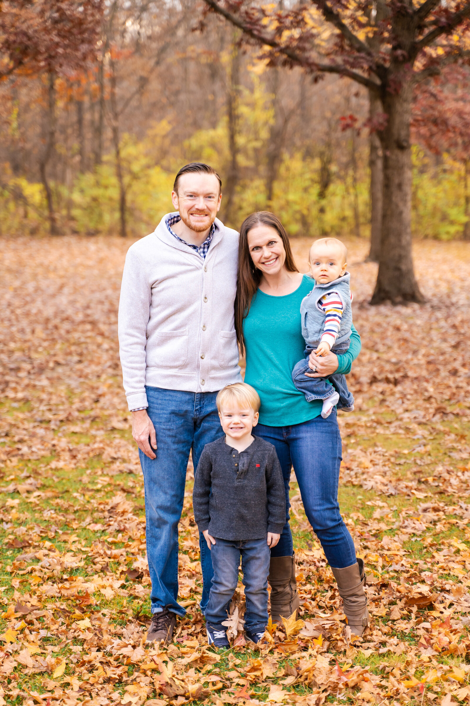 Family of four standing together in front of beautiful fall foliage at Sharon Woods in Westerville, Ohio.