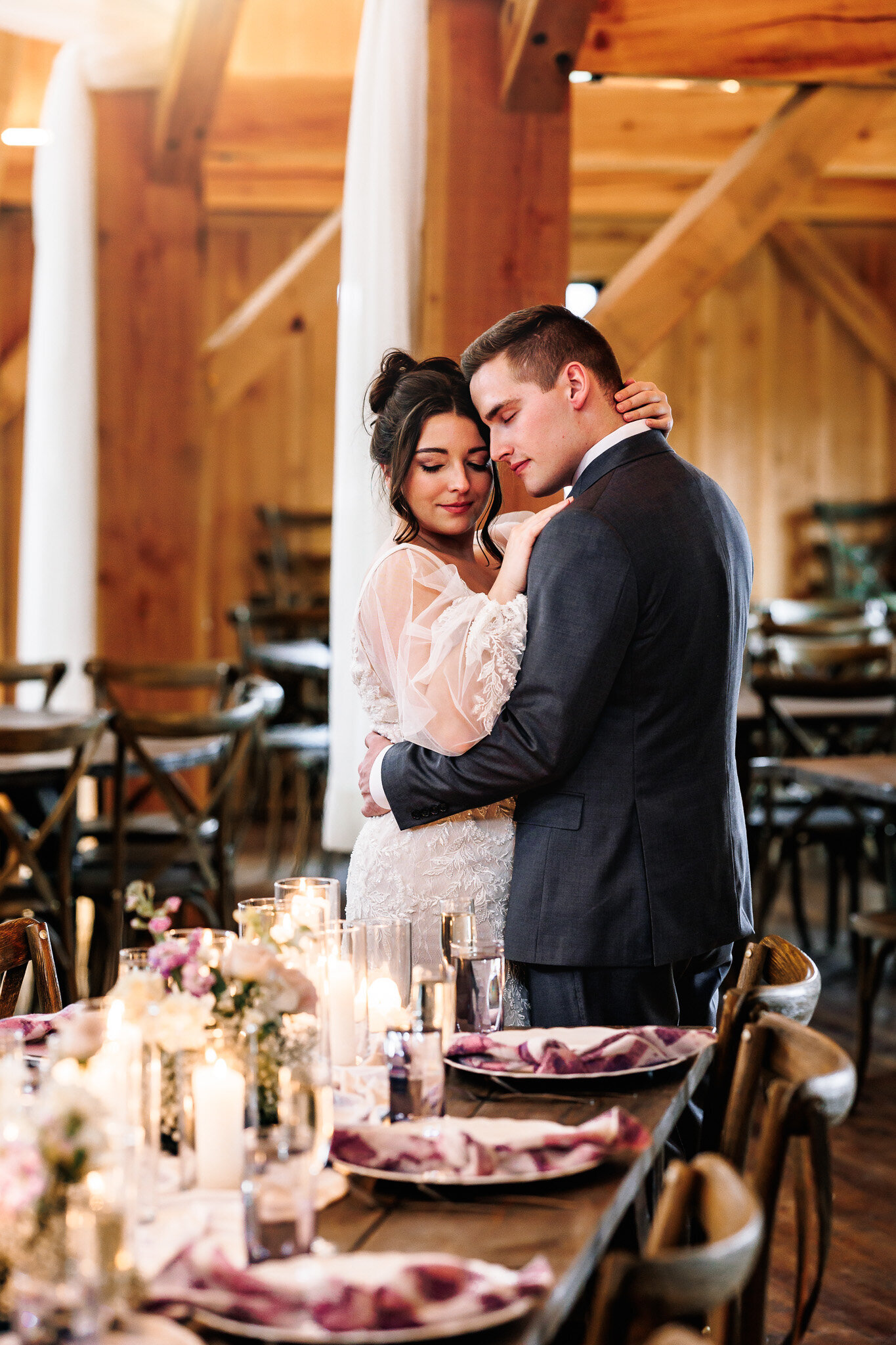 A newly wed couple holds each other close amongst the beautiful decor of their wedding reception 